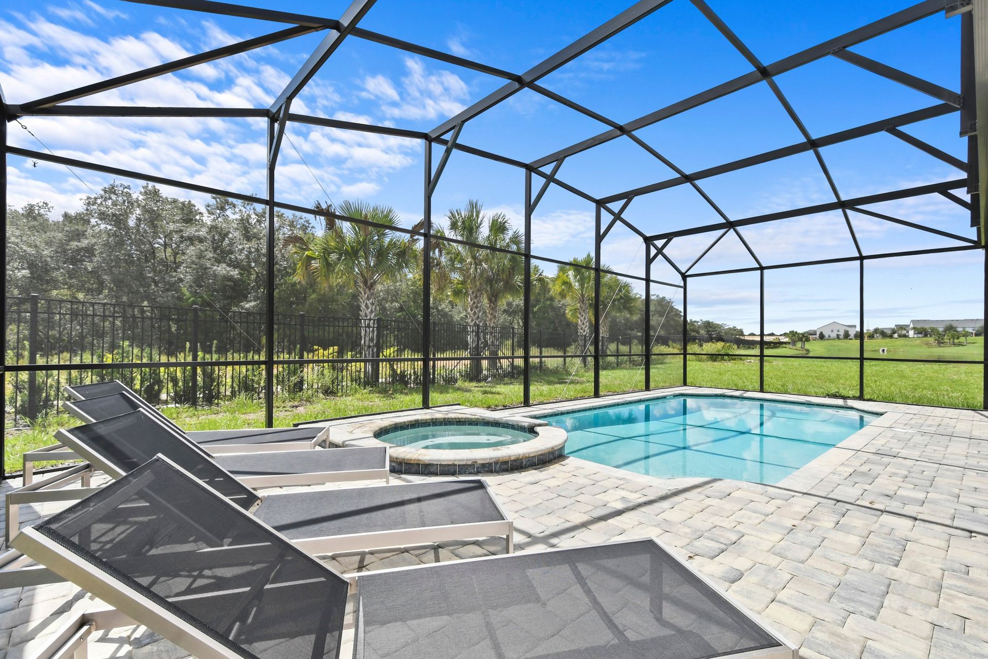 Screened-in private pool and spa with sun loungers and serene nature views.