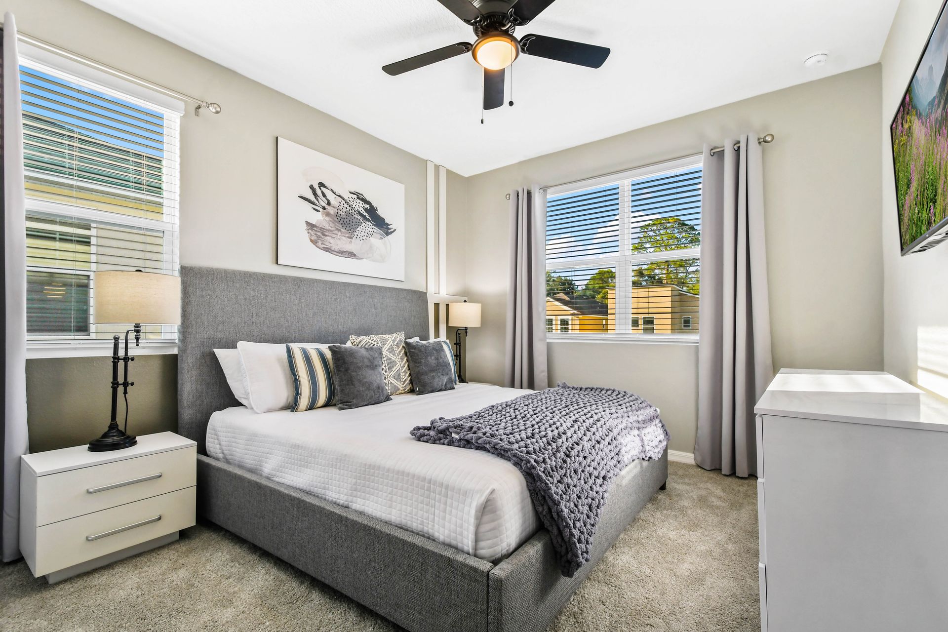 Modern bedroom with soft gray tones, plush bedding, and natural light!