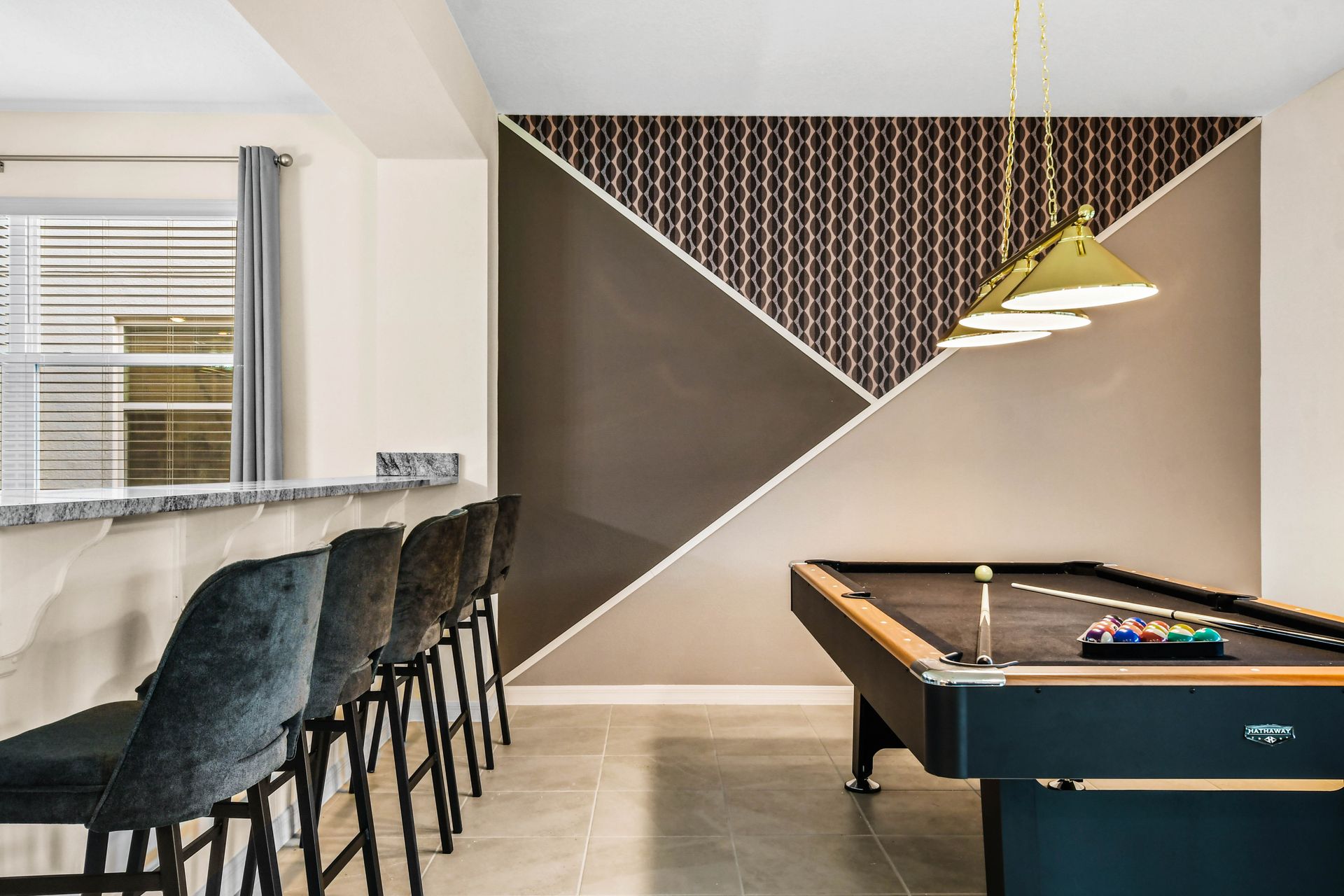 Modern game room with pool table, bar seating, and sleek design