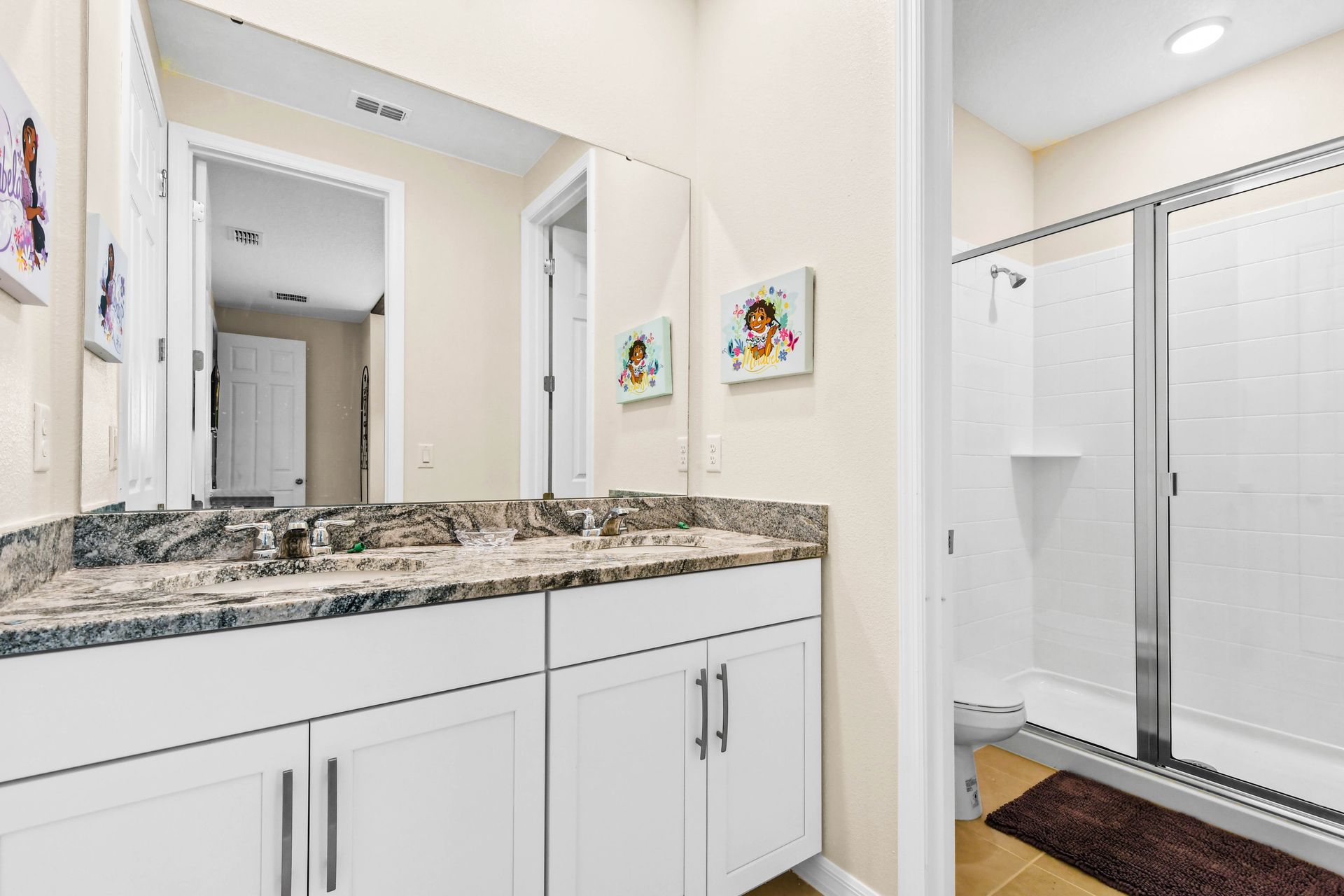 Charming shared bathroom with granite double vanity and fun Minions decor!