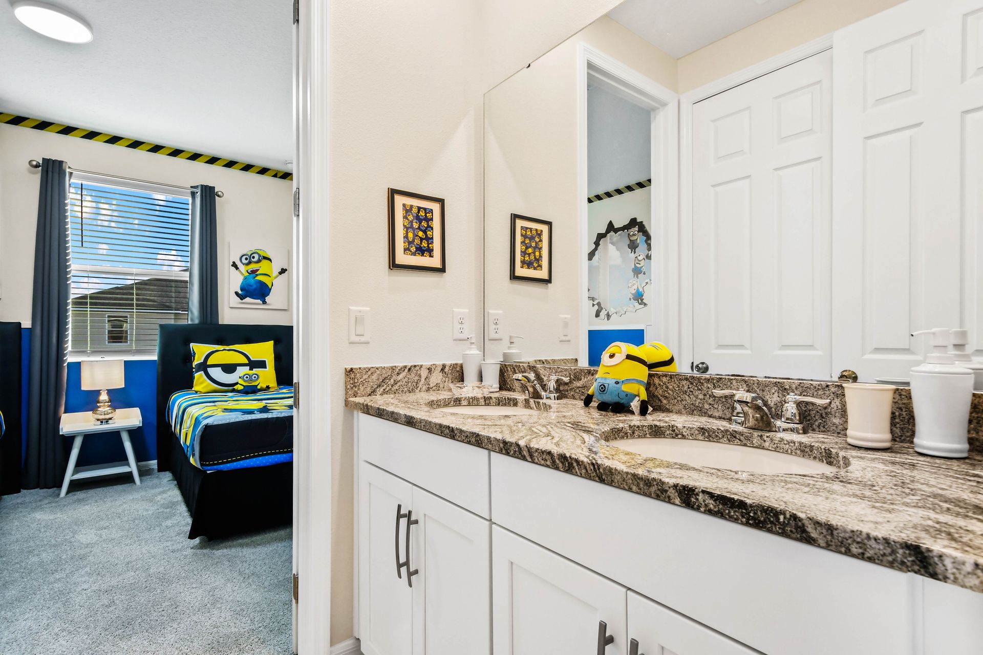 Bright bathroom with a granite double-sink vanity and a view into a cozy, elegant bedroom.
