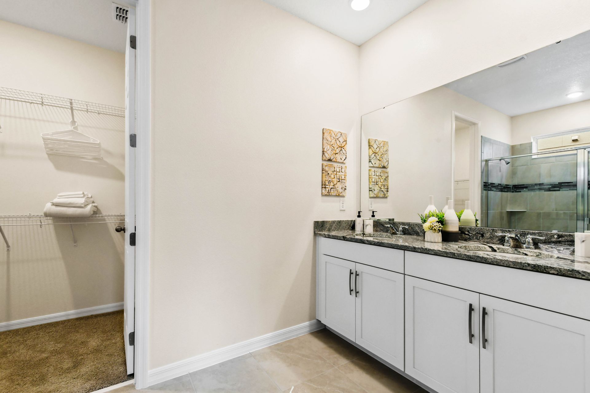 Modern bathroom with granite counters, bright window, and shower.