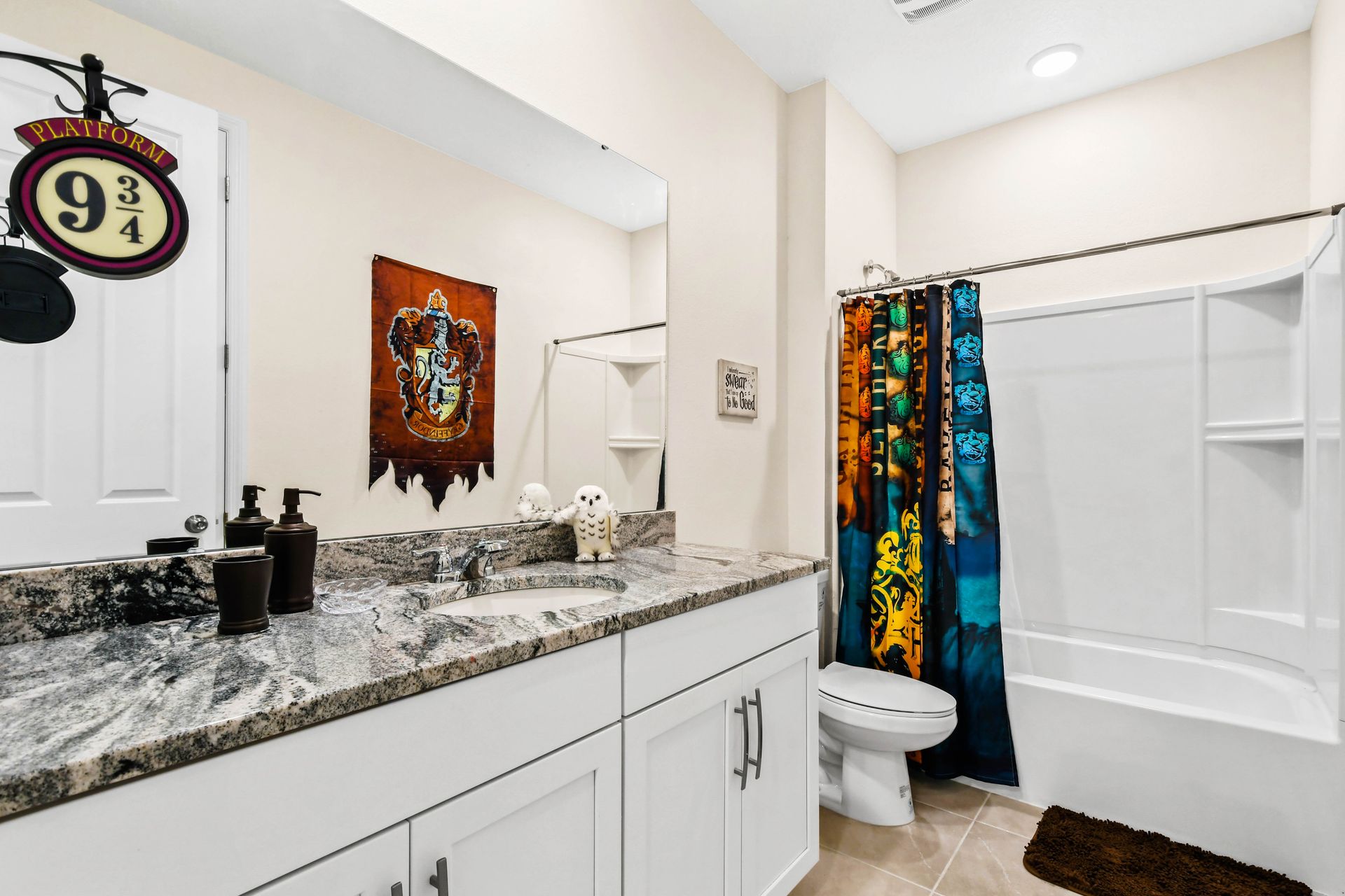 Themed bathroom with granite counters, bright window, and shower.