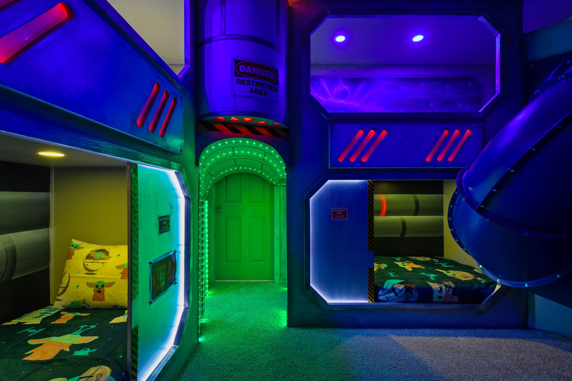 Futuristic space-themed bunk room with glowing lights and slides