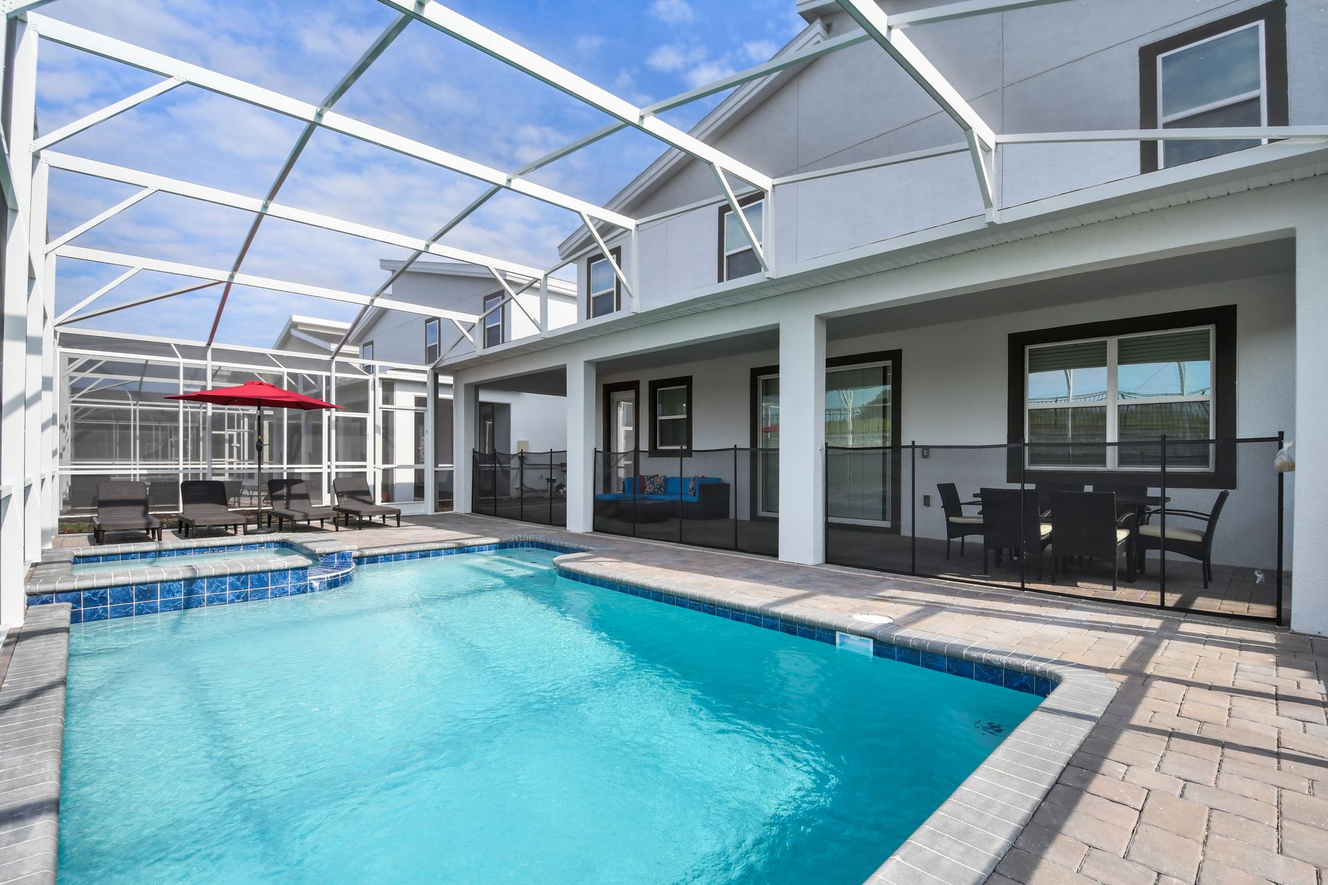 Spacious screened pool and spa with outdoor dining and lounge seating areas.