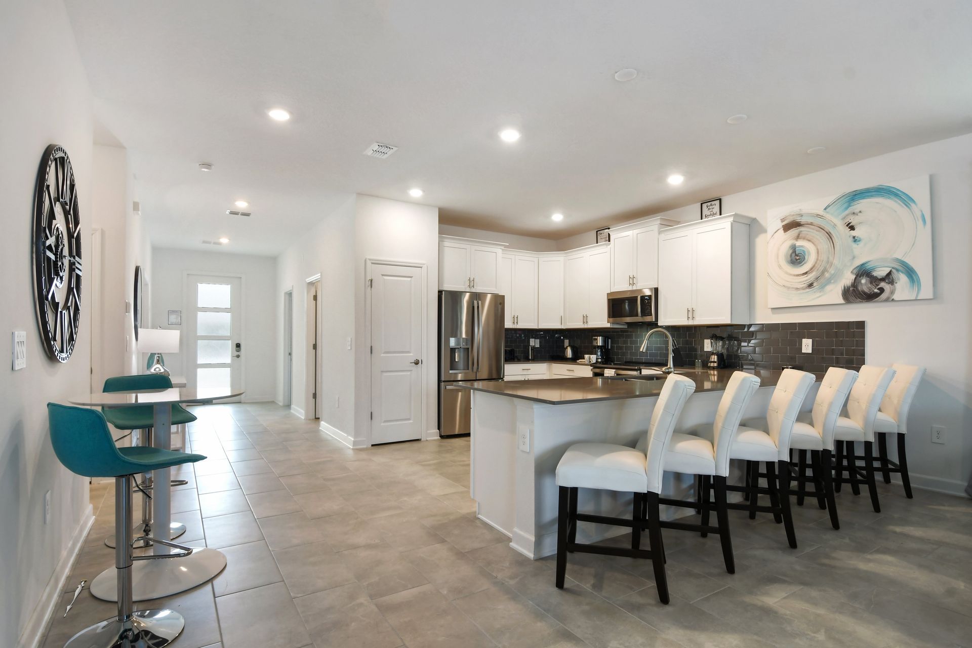 Bright modern kitchen with breakfast bar seating, stainless appliances, and bold art.