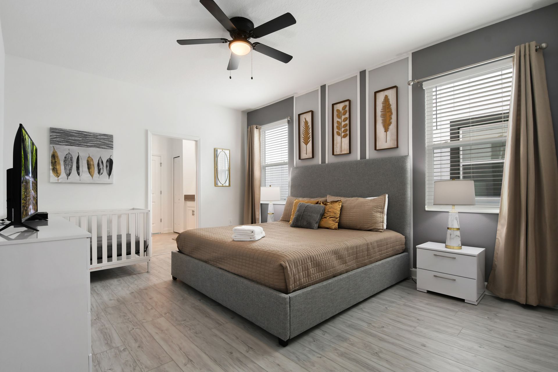 Serene bedroom with neutral tones, king bed, ensuite bath, and a cozy crib.
