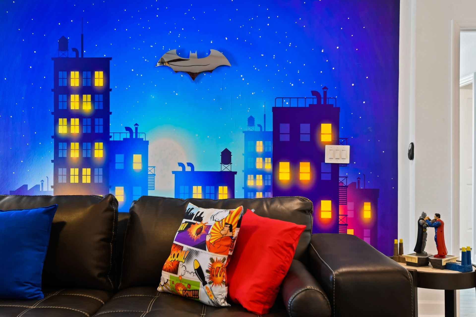 Colorful hero-themed wall with cityscape mural, comic pillows, and action figures.