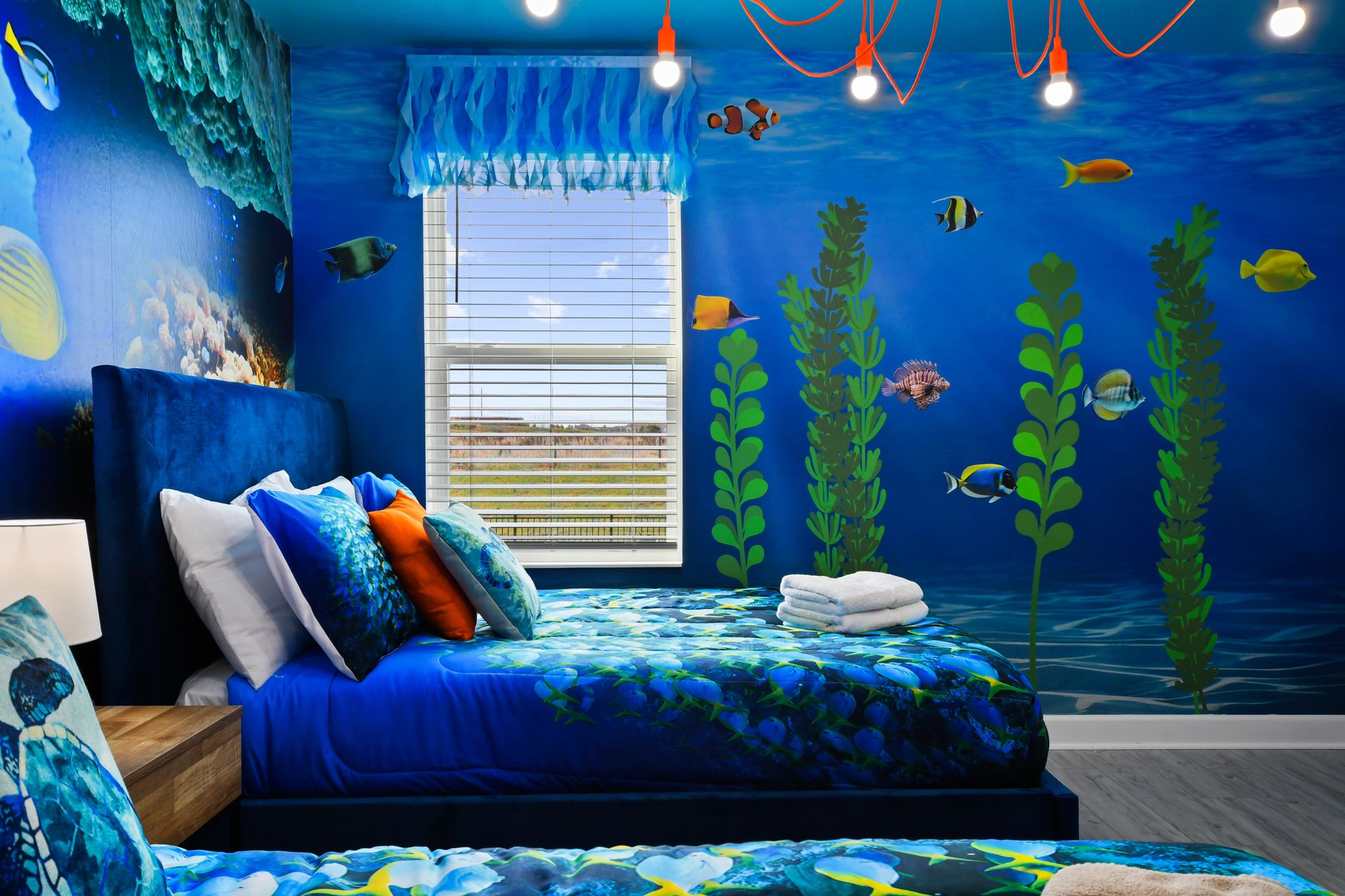Underwater-themed twin room with ocean murals, vibrant bedding, and playful lighting.