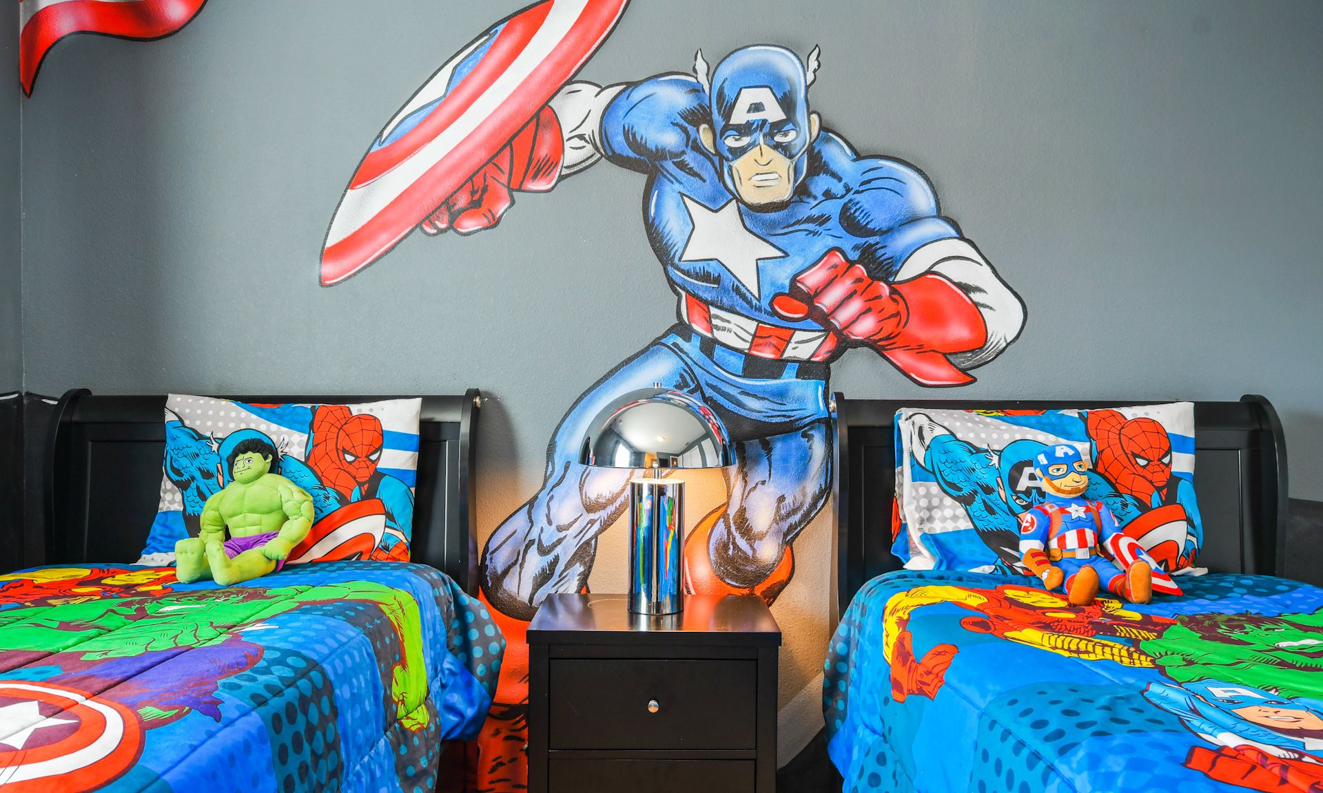 Hero-themed kids' room with vibrant decor, twin beds, superhero bedding, and fun wall art.