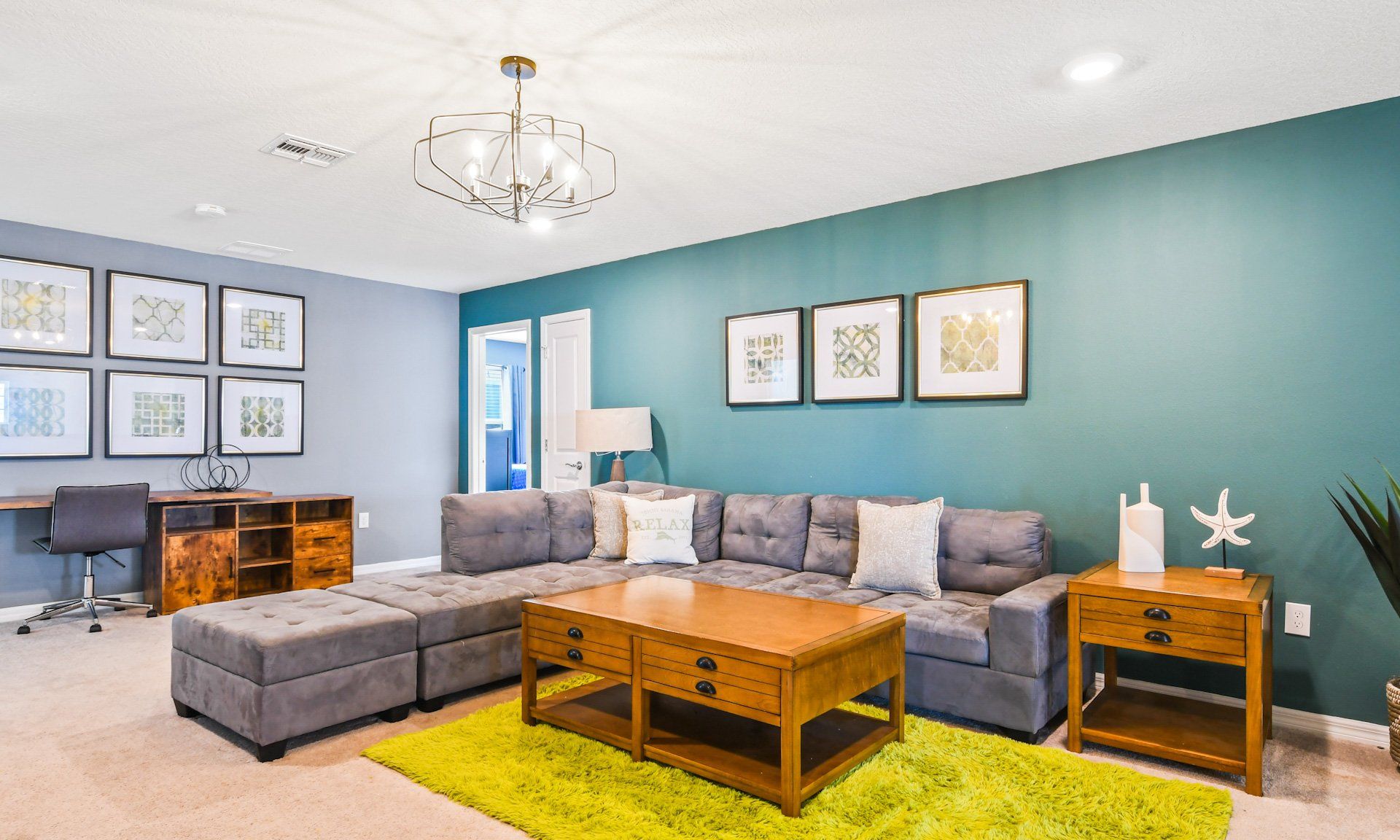 Stylish lounge area with plush sectional sofa, vibrant decor, cozy workspace, and modern lighting.