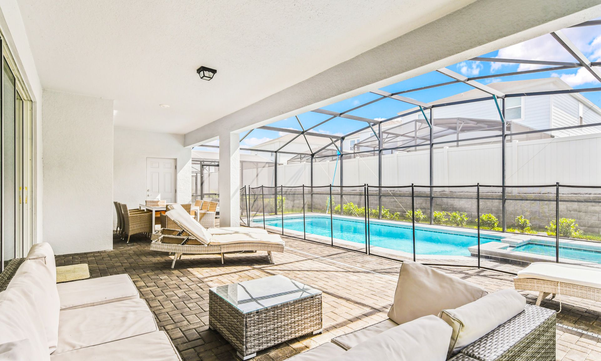 Covered patio with cozy lounge seating, dining area, and private screened pool for ultimate relaxation.