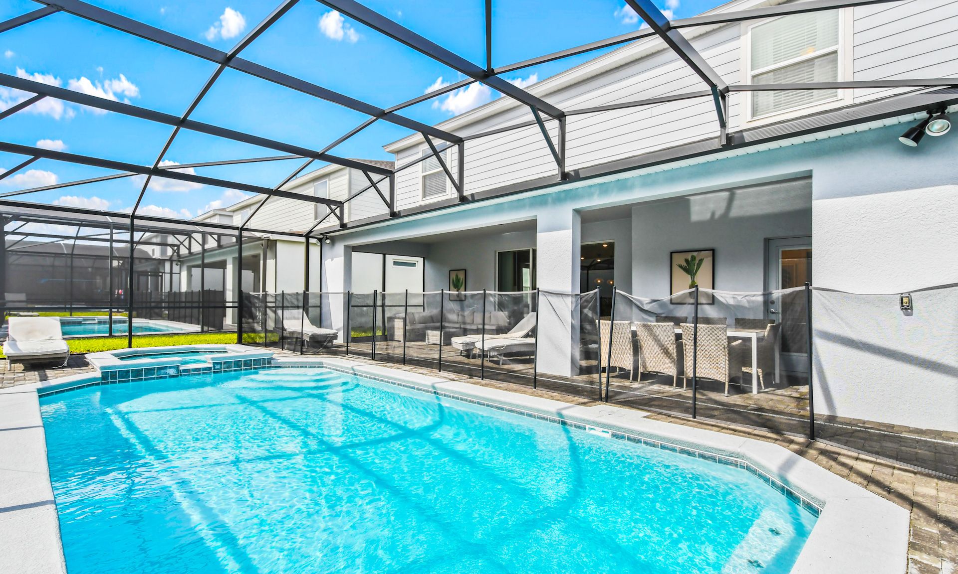 Spacious screened pool area with hot tub, sun loungers, and shaded patio seating for ultimate relaxation.