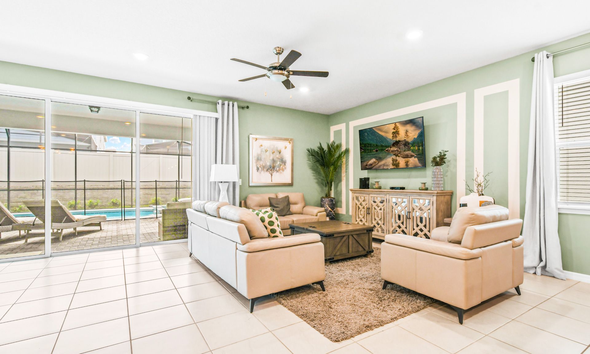 Bright living room with plush seating, stylish decor, smart TV, and direct access to the pool area.