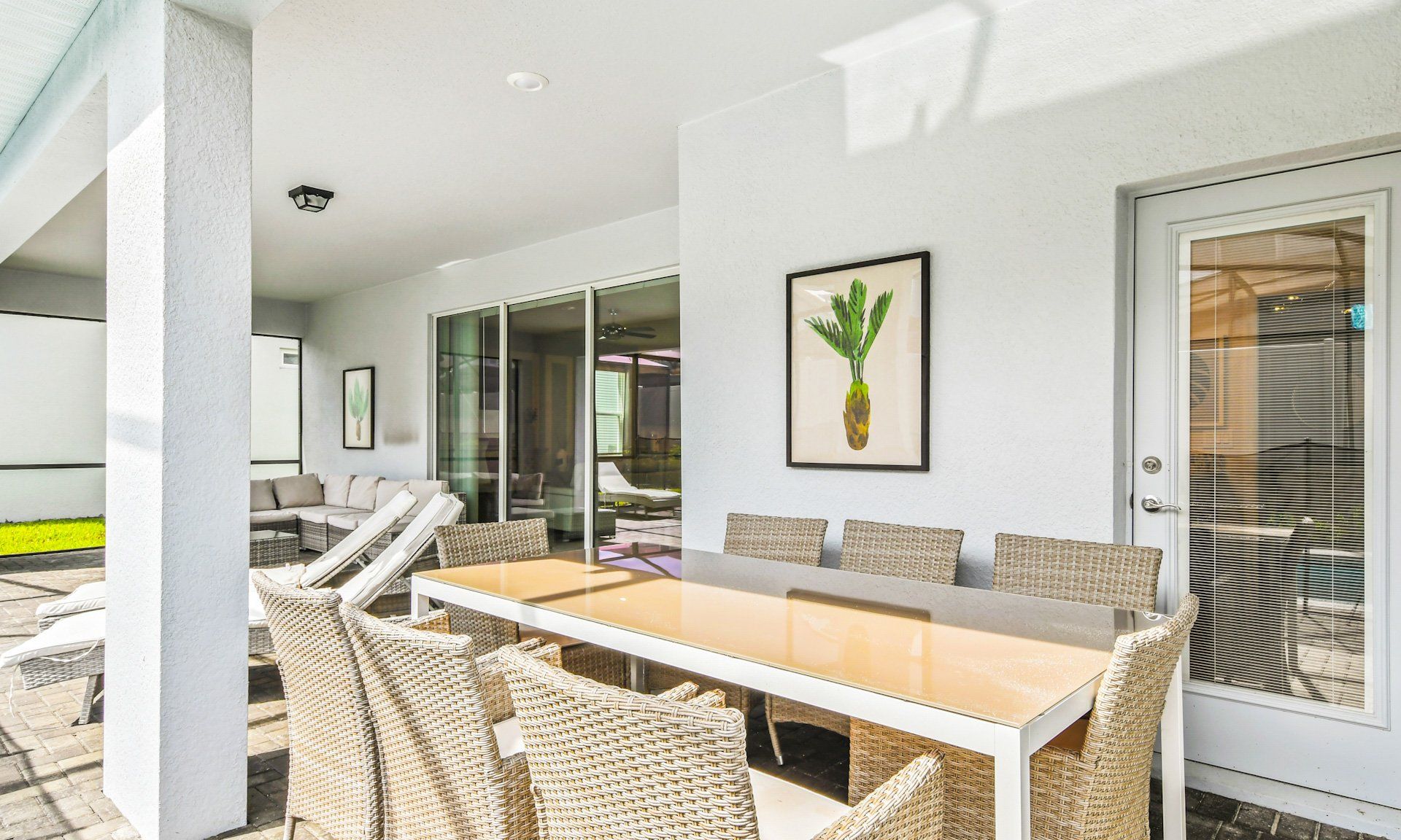 Covered outdoor dining area with stylish wicker seating, lounge chairs, and cozy sectional for relaxation.