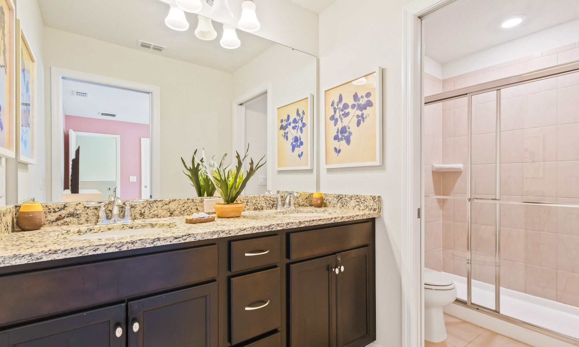 Elegant bathroom with granite double vanity, floral artwork, and glass-enclosed shower for a refreshing feel.