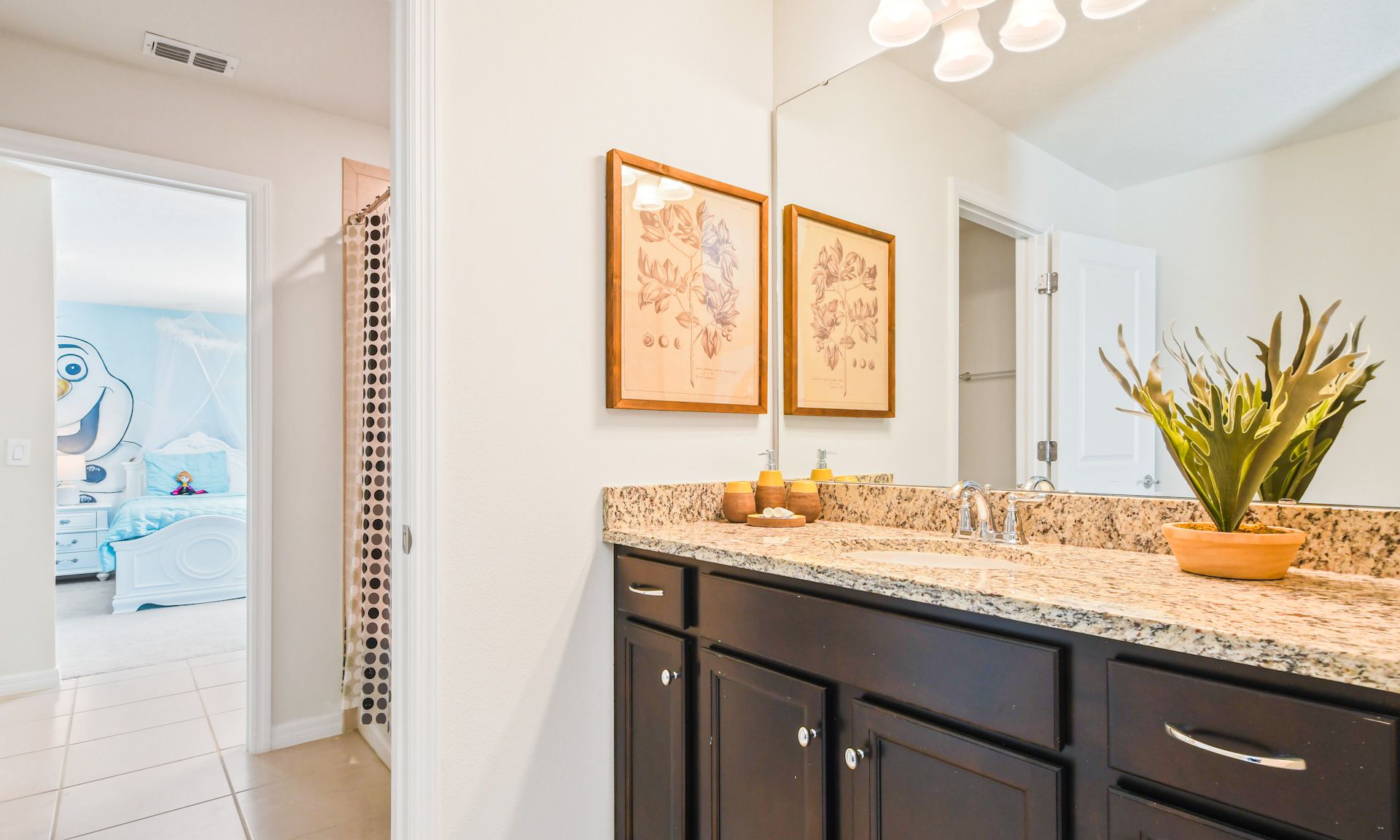 Bright bathroom with granite countertop, stylish decor, and access to a fun Frozen-themed kids' room.