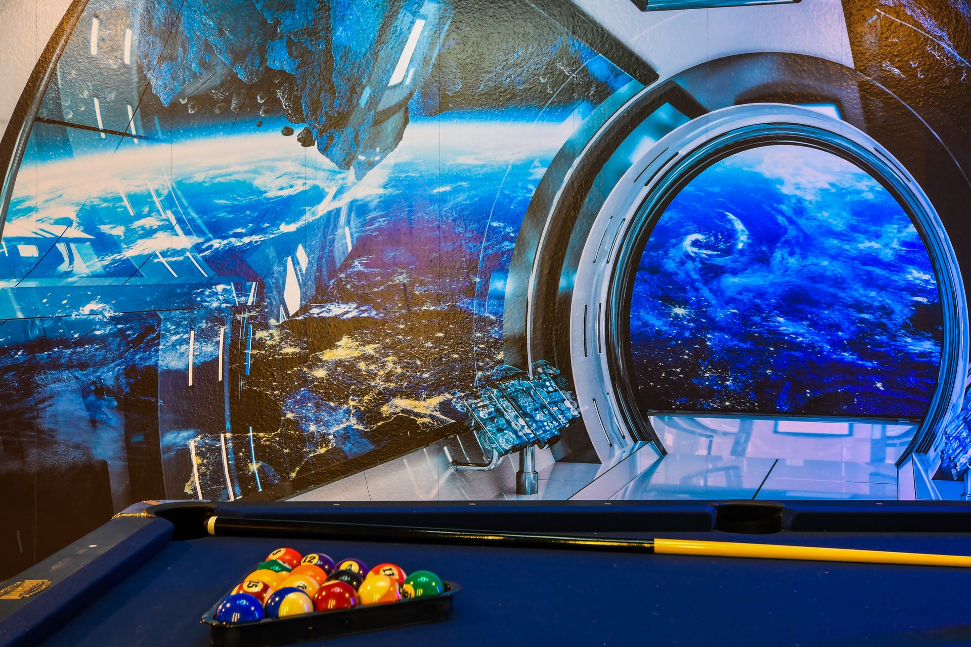 Space-themed game room with pool table and stunning galaxy wall mural atmosphere