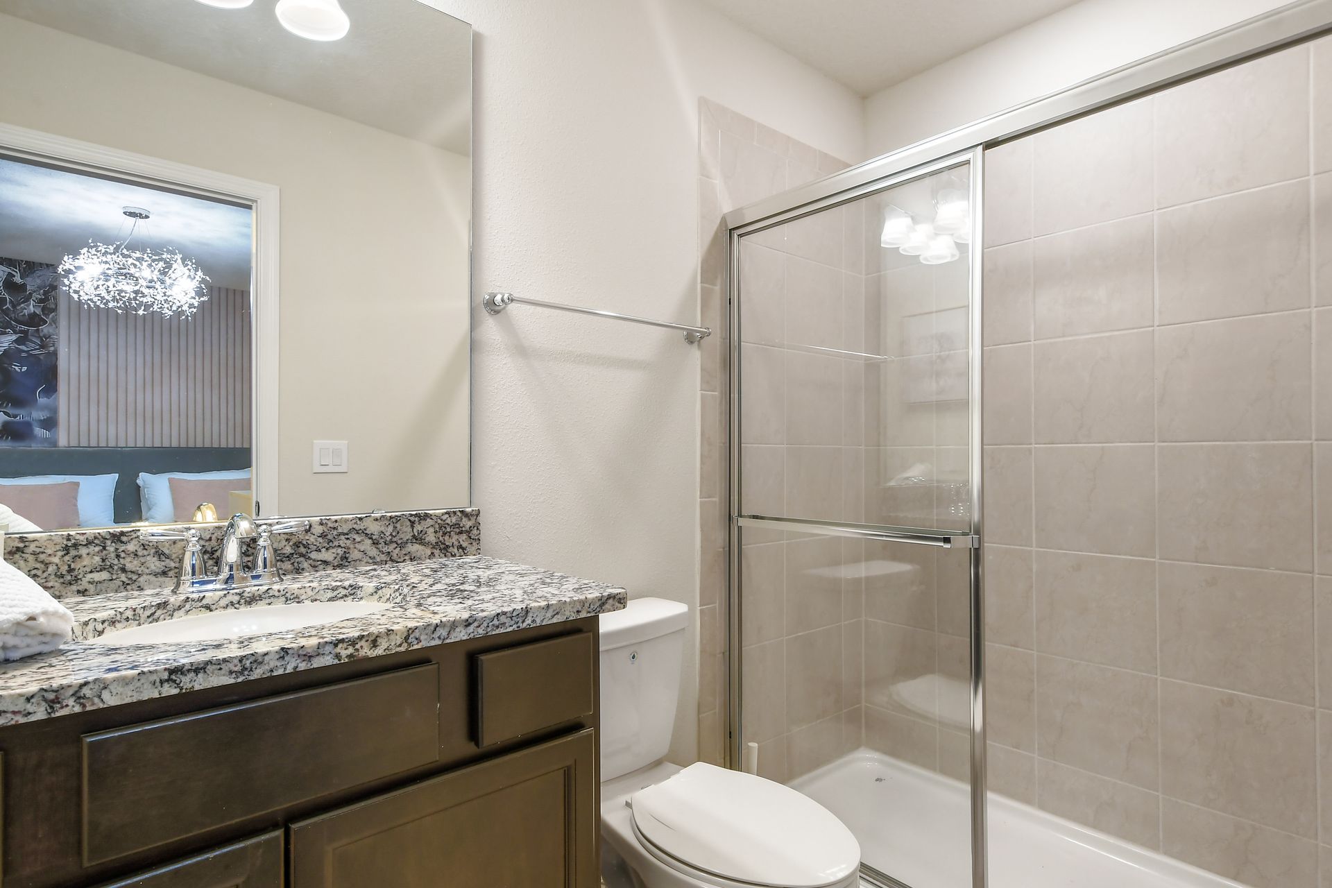 Elegant bathroom with granite counter, glass shower, and view of stylish bedroom