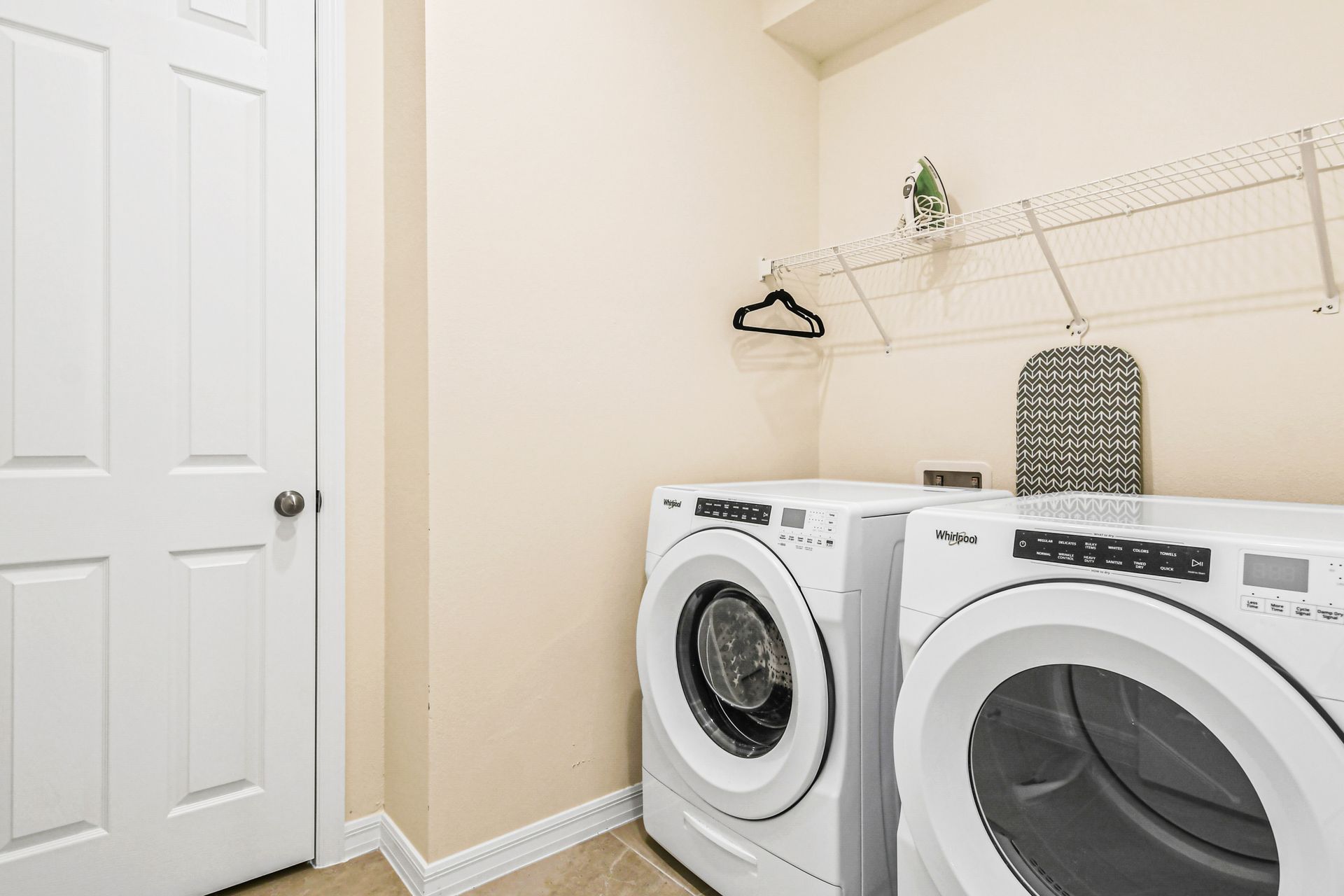 Compact laundry room featuring a washer and dryer with a handy wire shelf for storage.