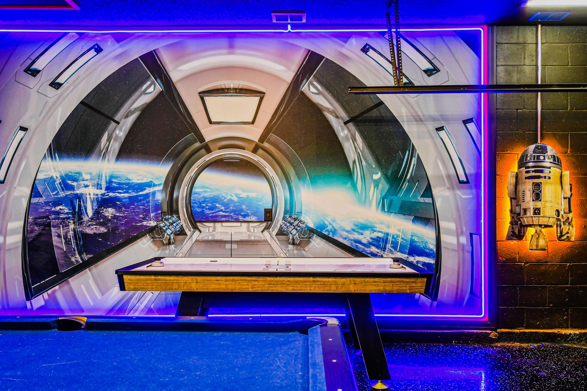Futuristic space-themed game room with glowing decor and R2-D2.