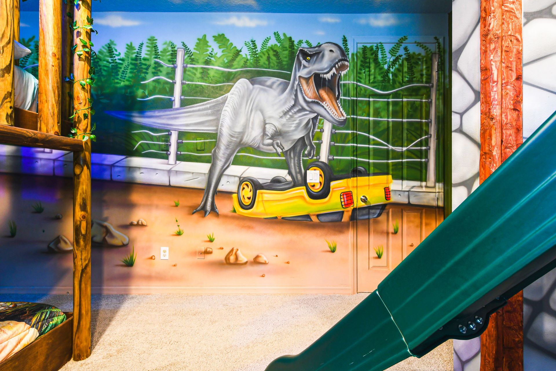 Dinosaur-themed room with vibrant mural, slide, and bunk beds!