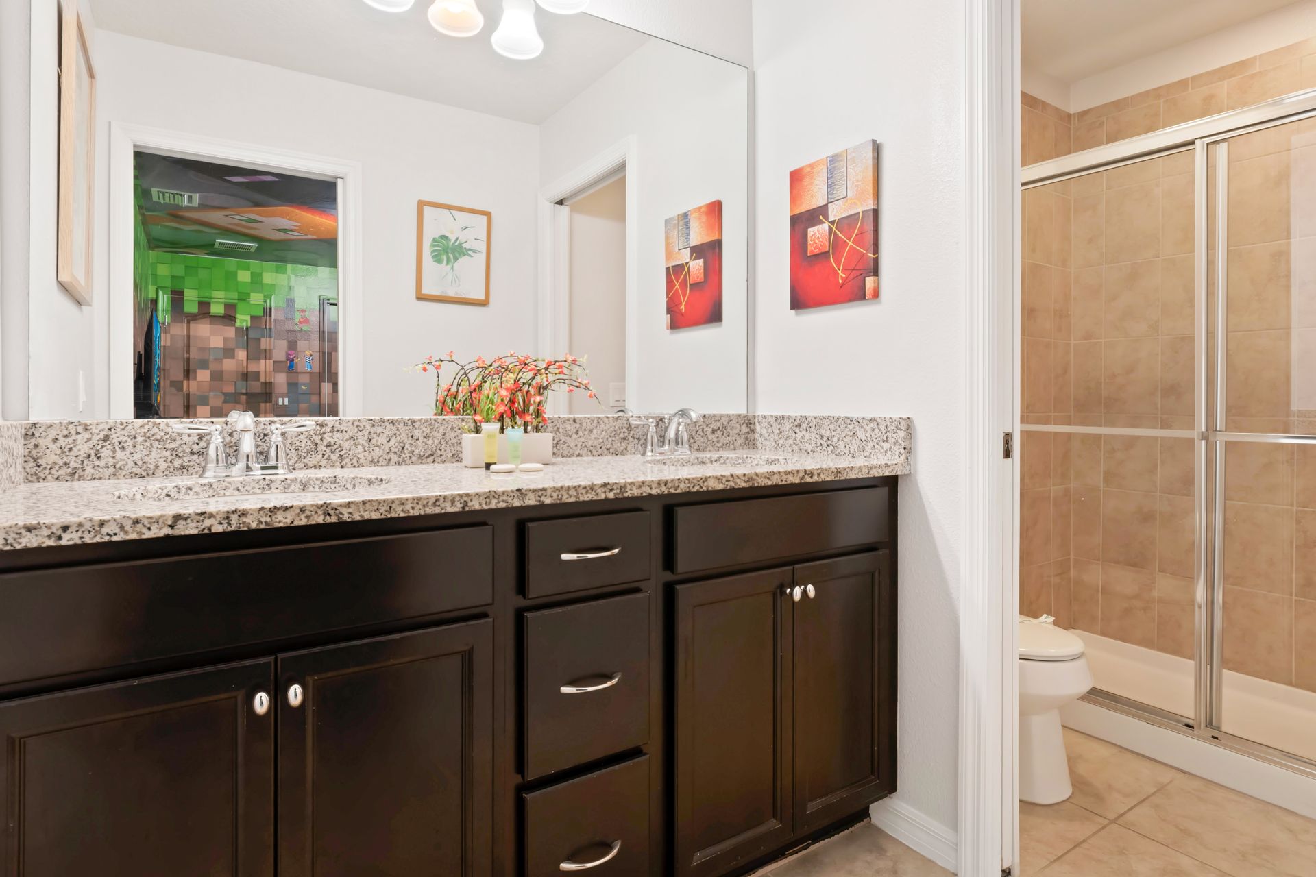Modern bathroom with dual sinks, granite counters, and spacious tiled shower.