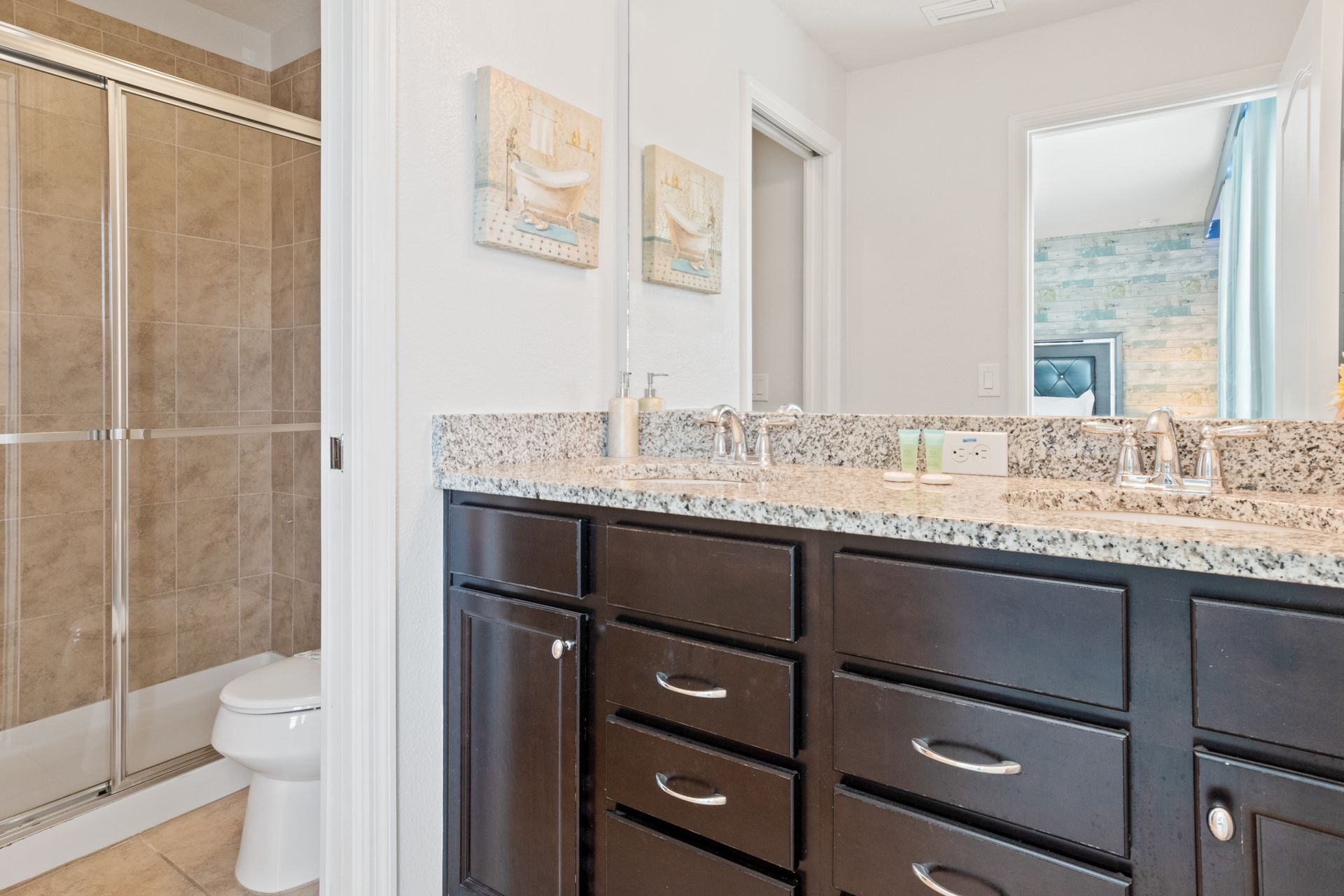 Spacious bathroom with double sinks, granite counters, and a sleek tiled shower.