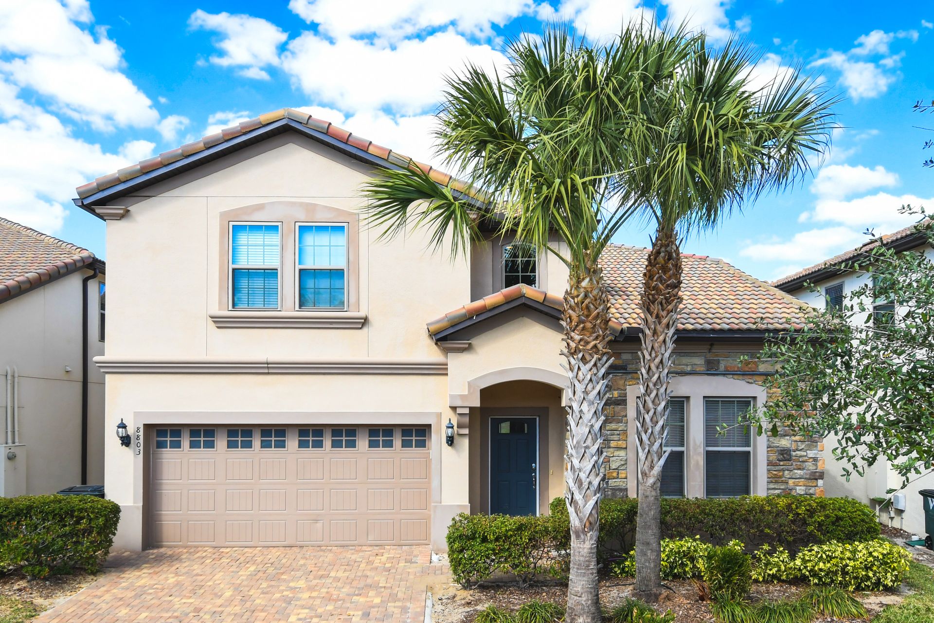 Elegant villa with palm-lined entrance, private garage, and beautiful tiled roof.