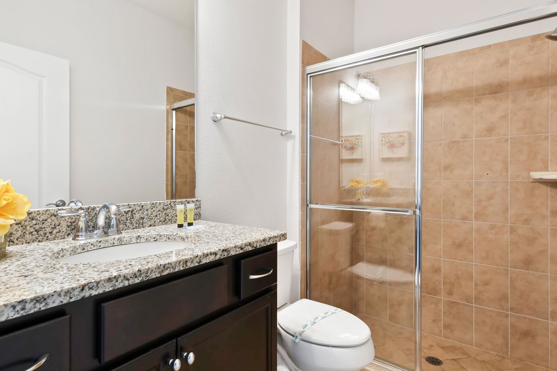 Modern bathroom with granite counters and a sleek, tiled walk-in glass shower.