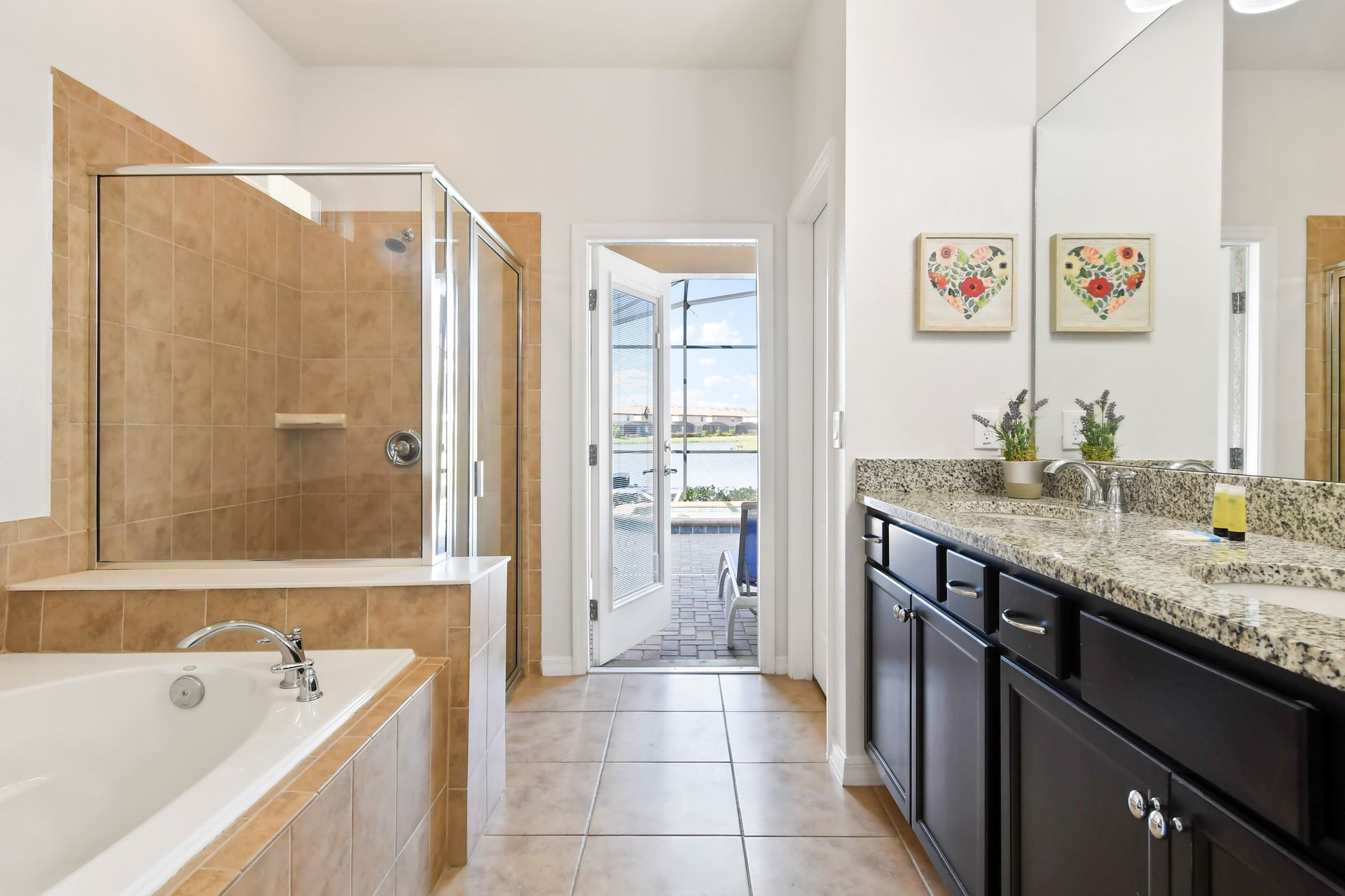 Bright master bath with soaking tub, double vanity, and direct poolside access.