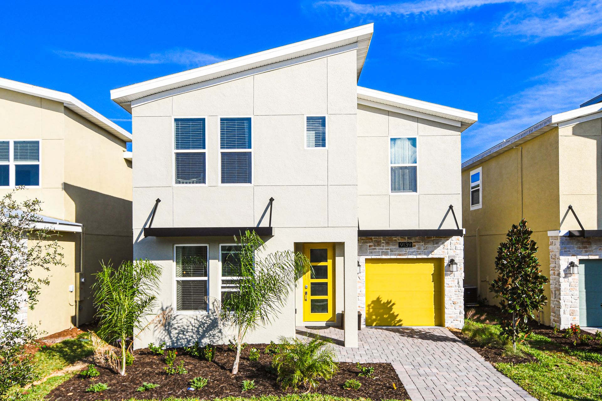 Bold modern home with bright yellow accents and fresh tropical landscaping.