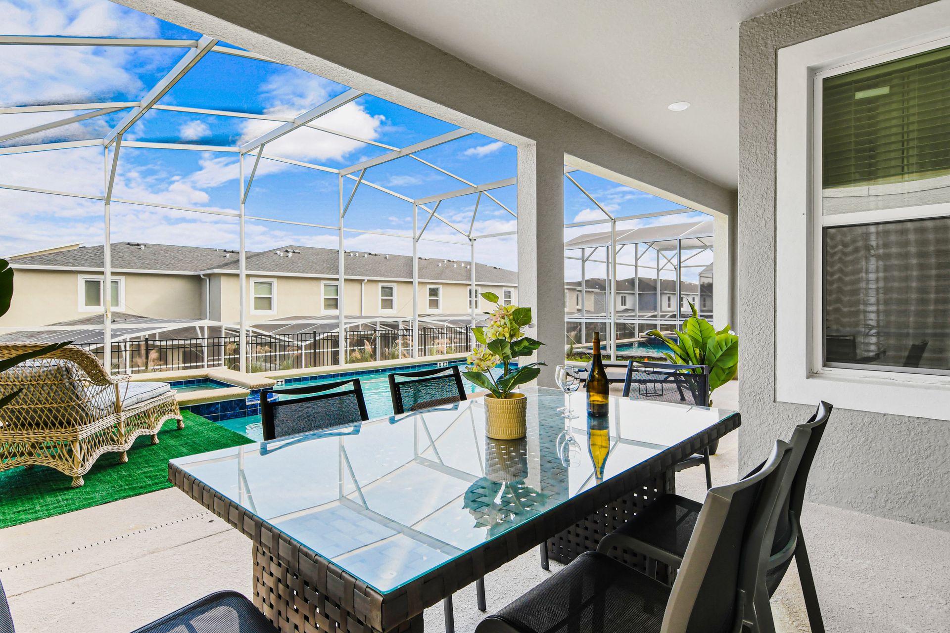 Poolside screened patio with glass dining table, lounge chairs, and sunny views.
