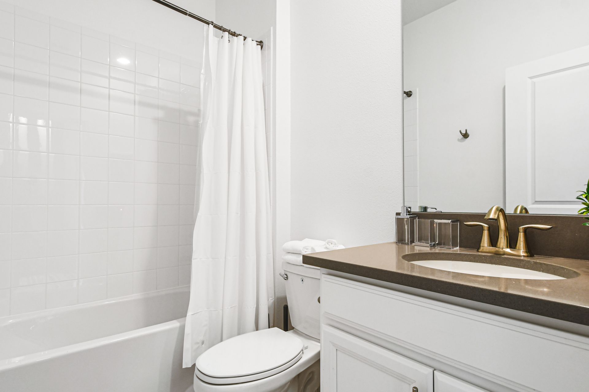 Bright bathroom with dual sinks, walk-in shower, and elegant gold fixtures.