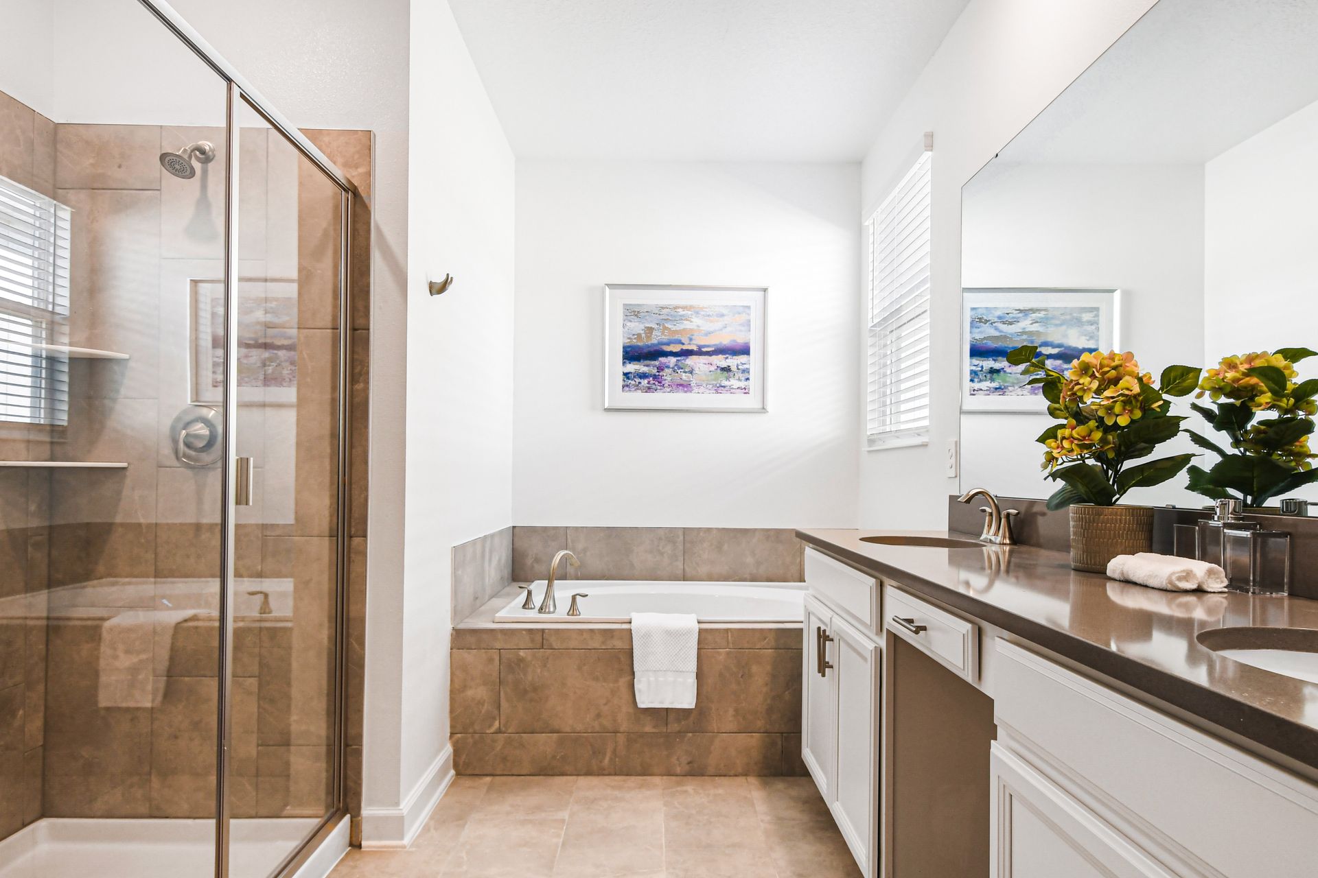 Luxurious bath with dual sinks, glass shower, and bright natural light.