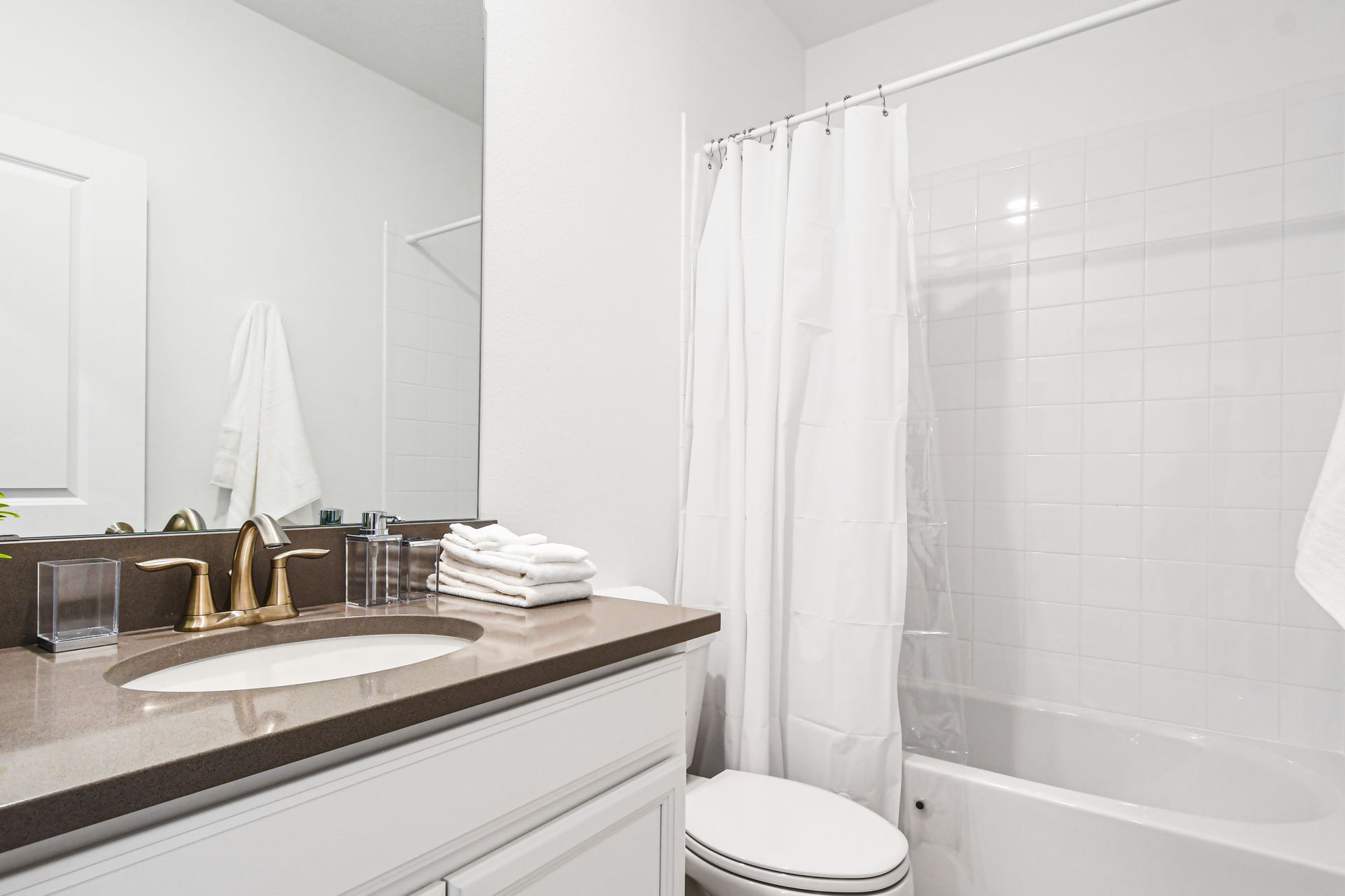 Bright full bath with simple style, cozy shower curtain, and soft accents.