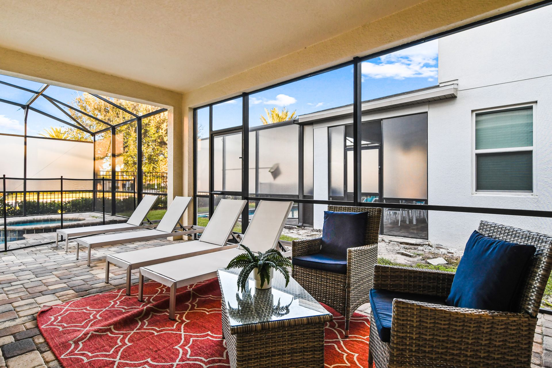 Screened patio with cozy seating, sun loungers, and pool views for relaxing days.