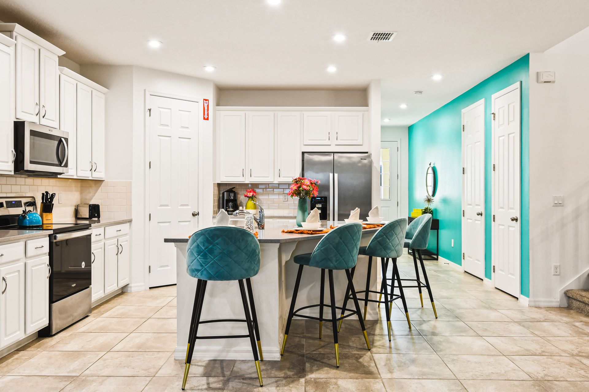 Modern kitchen with bright accents, island seating, and stainless steel appliances.