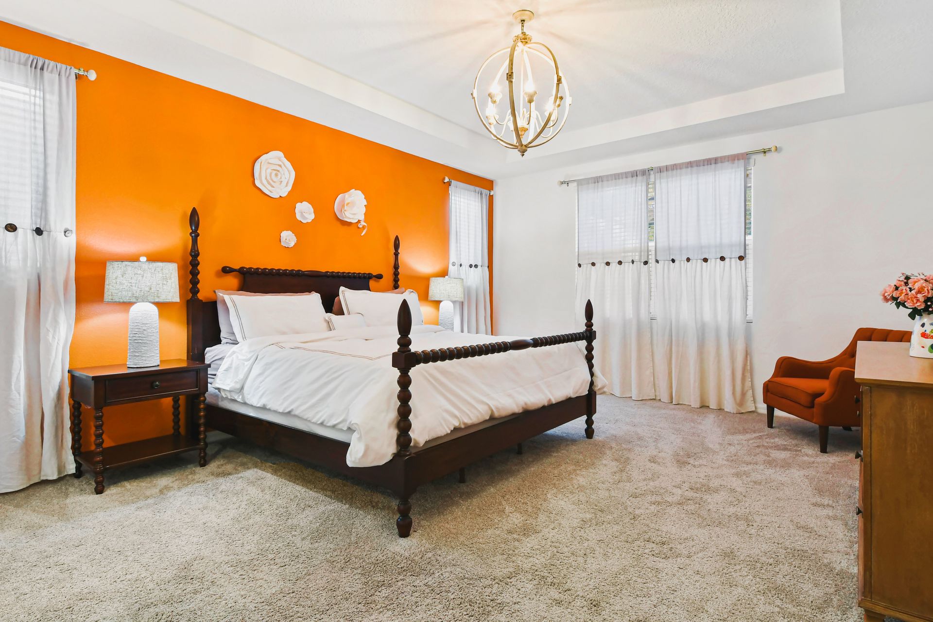Bright bedroom with bold orange accent wall, elegant decor, and a cozy atmosphere.
