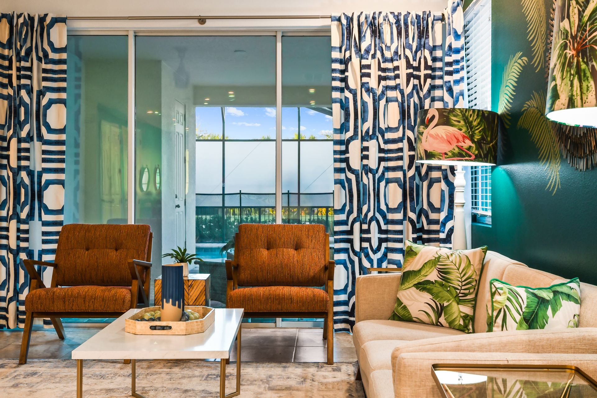 Tropical-inspired living room with bold patterns, cozy seating, and pool views.