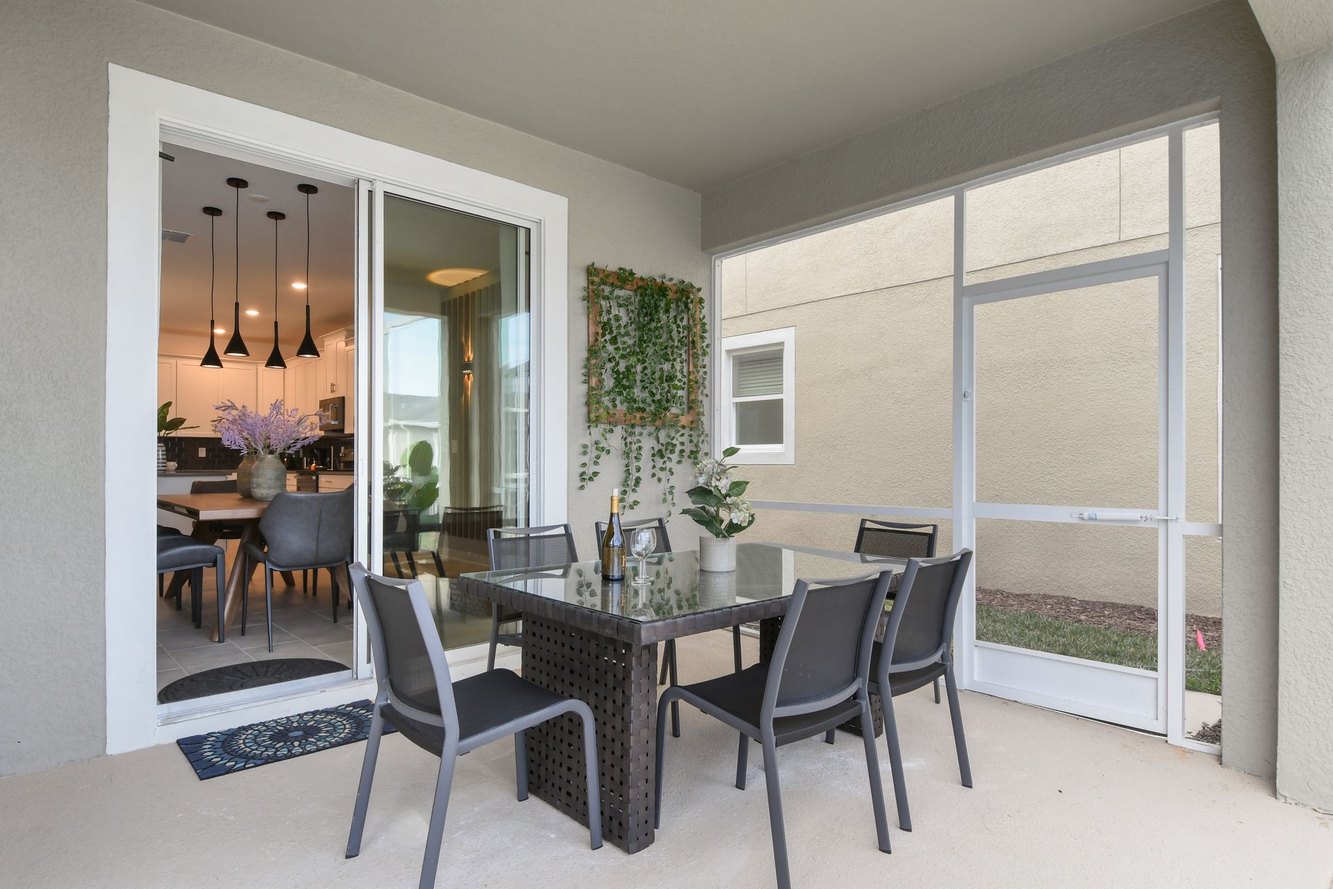Screened-in patio with modern dining set, greenery, and seamless indoor access.
