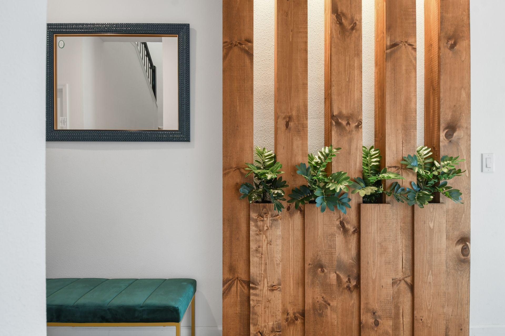 Stylish wall planter with wood slats and soft bench sets a calming tone.