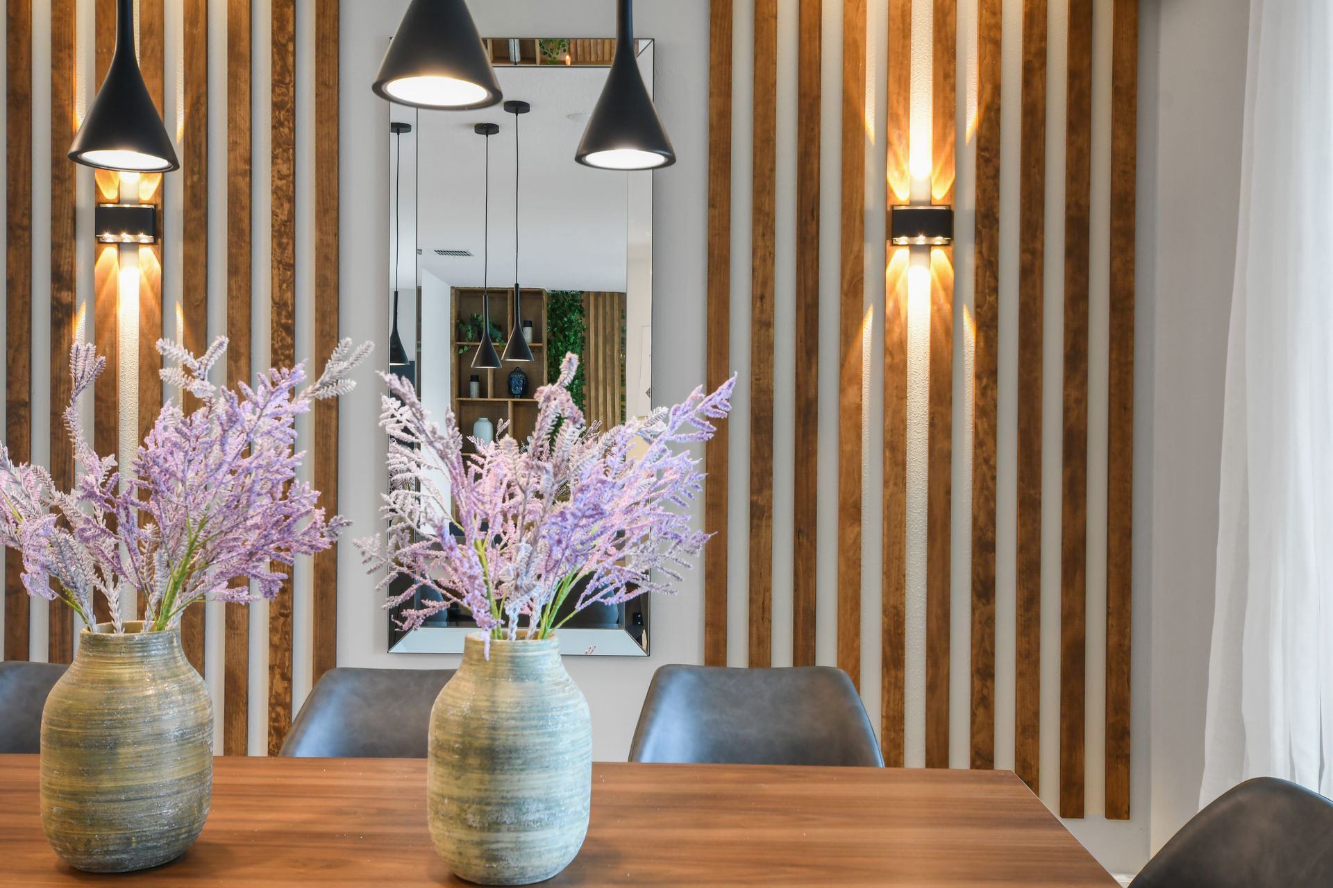 Modern dining room with wood accents, pendant lights, and floral touches.