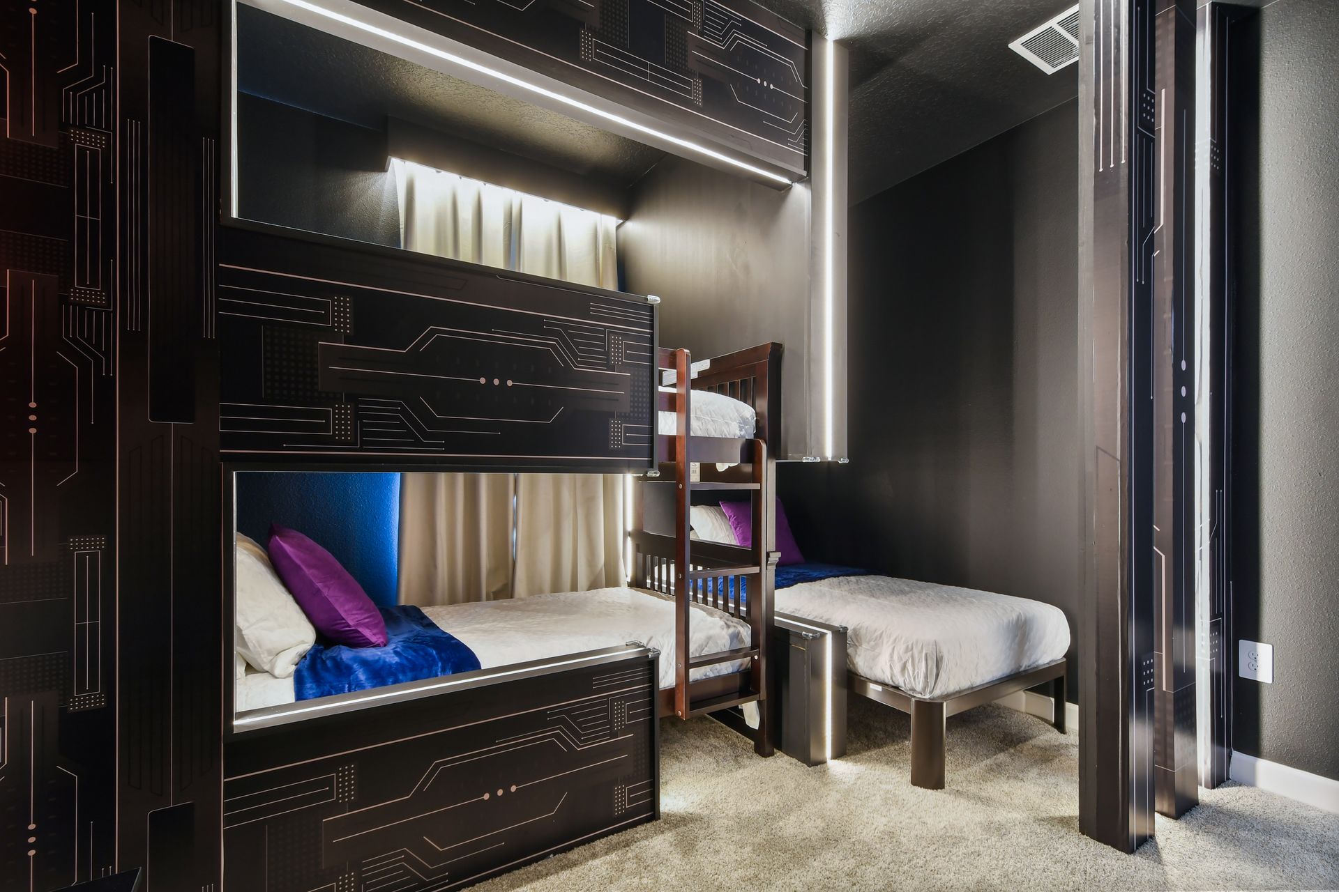 Futuristic bunk room with sleek lighting, space-themed design, and cozy beds.
