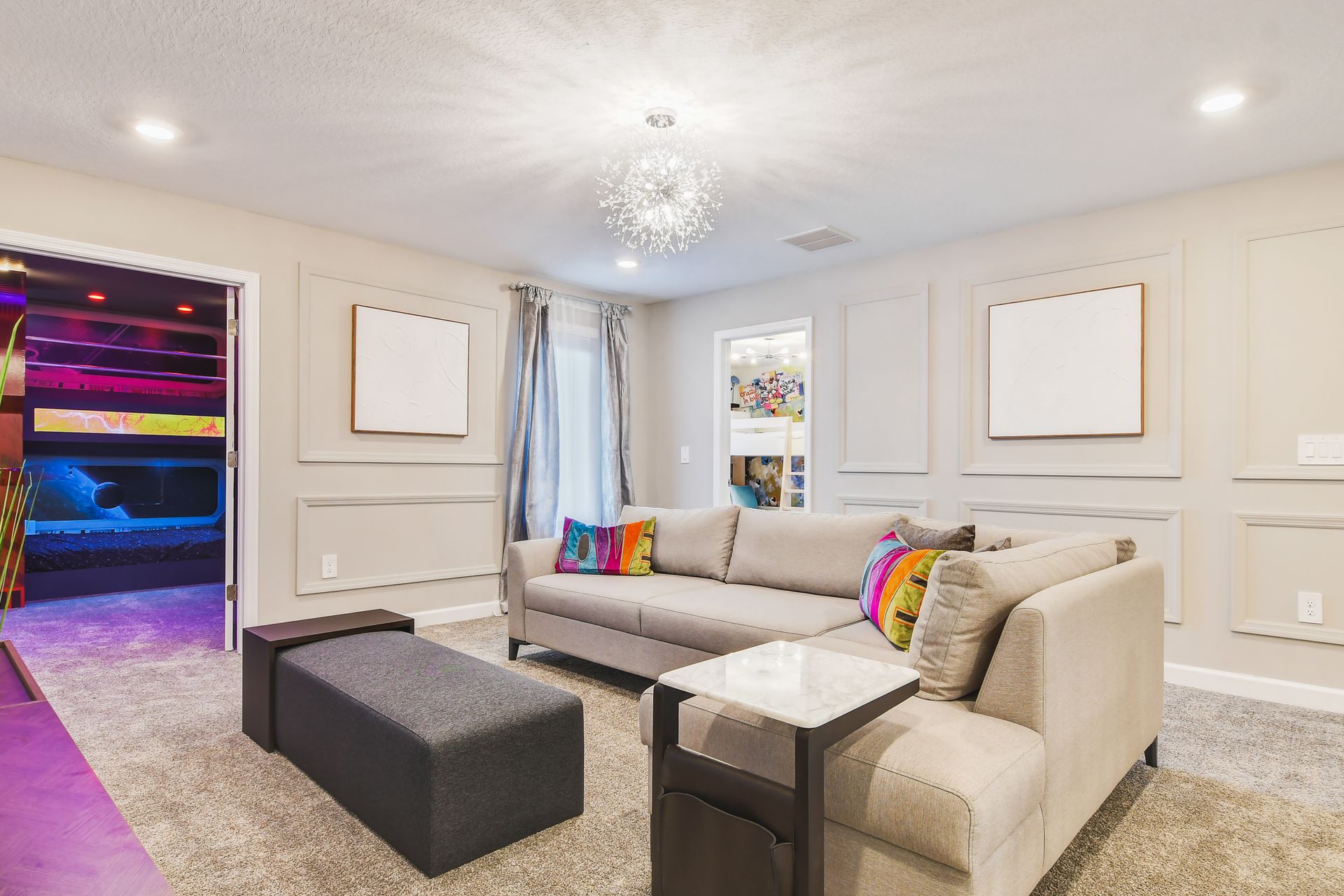 Bright upstairs loft with modern decor, cozy sectional, and access to themed rooms.