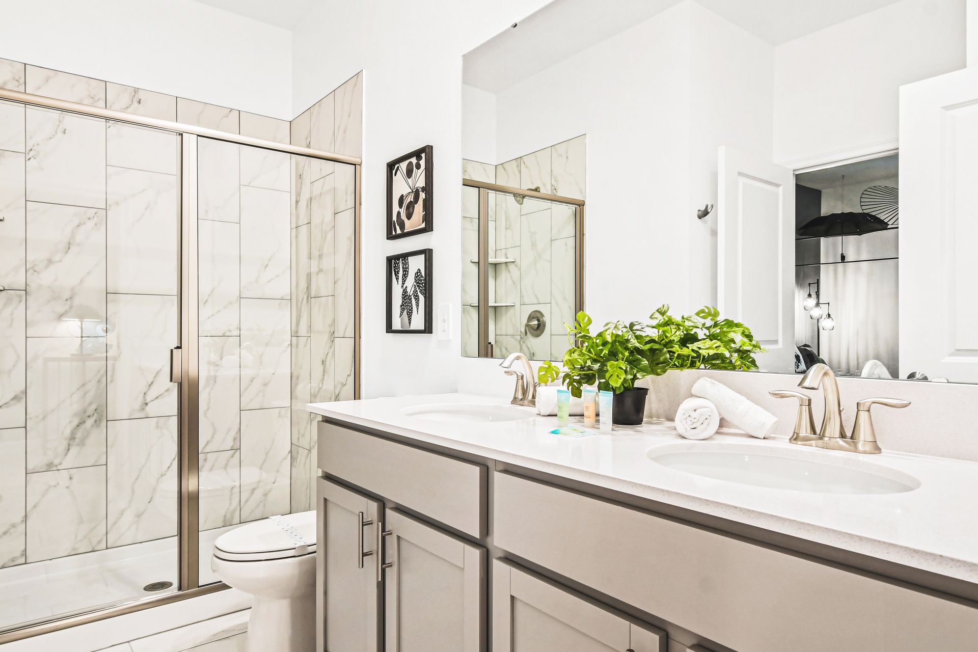 Sleek double-vanity bathroom with glass walk-in shower and modern marble tile.