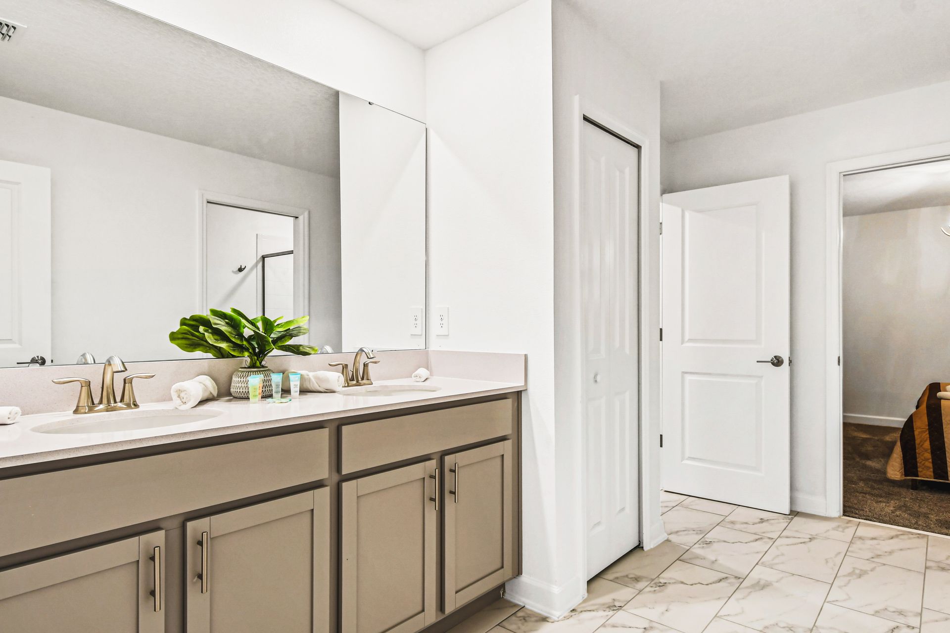 Bright ensuite bathroom with dual sinks, marble floors, and modern finishes.