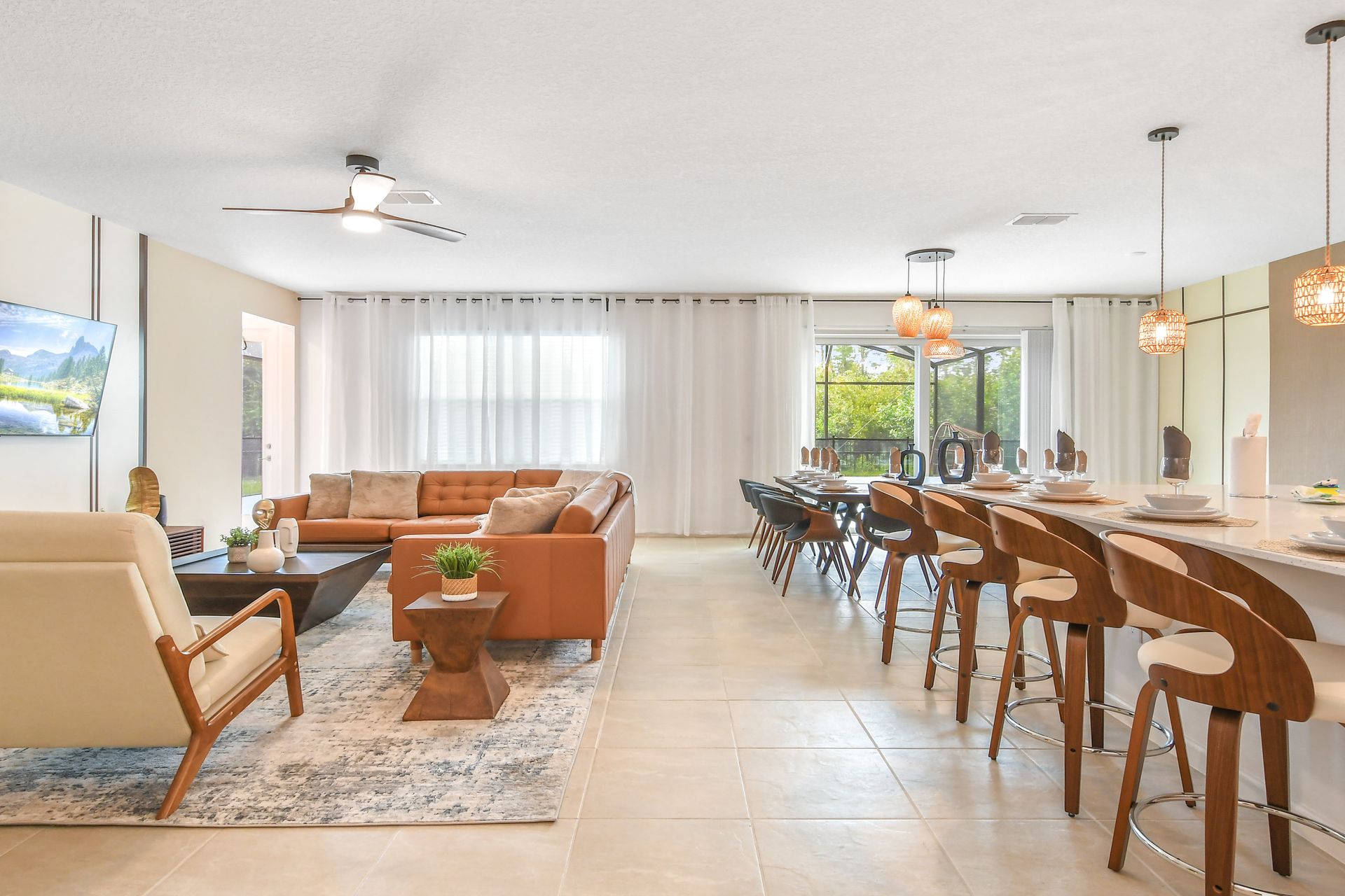 Open-plan living, dining, and kitchen area with modern furniture, warm lighting, and natural tones.