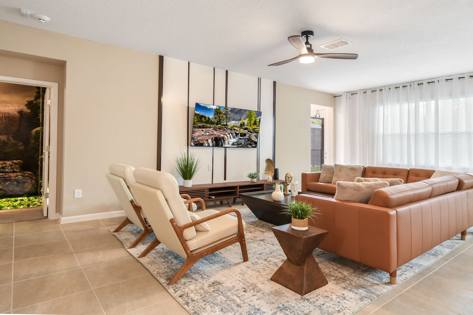 Modern living room with cozy seating, serene decor, and a glimpse of a dinosaur-themed room.