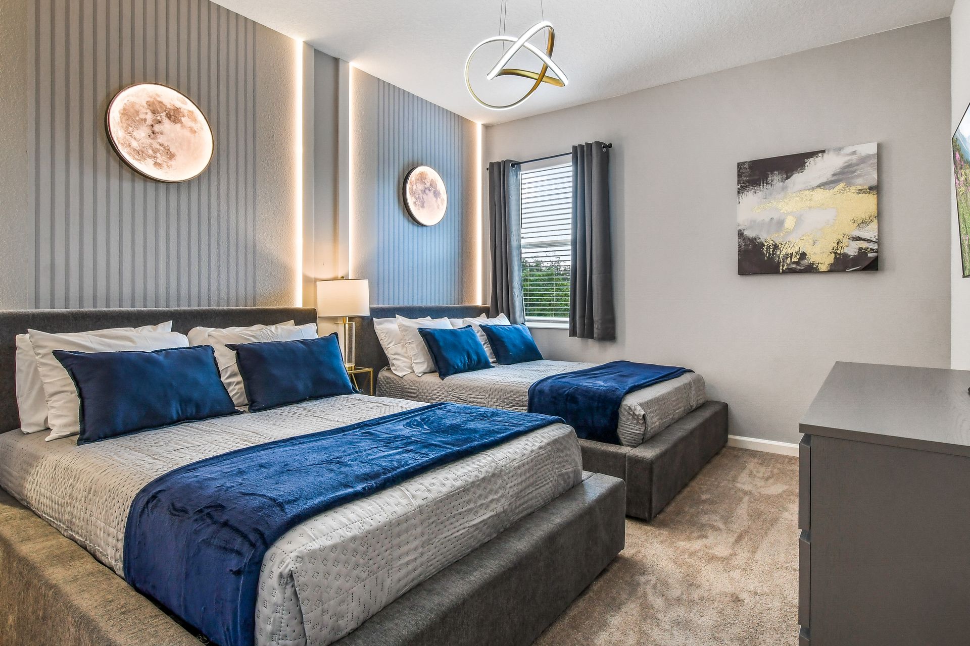 Elegant modern bedroom with moon-inspired wall decor, plush blue accents, and sleek lighting.